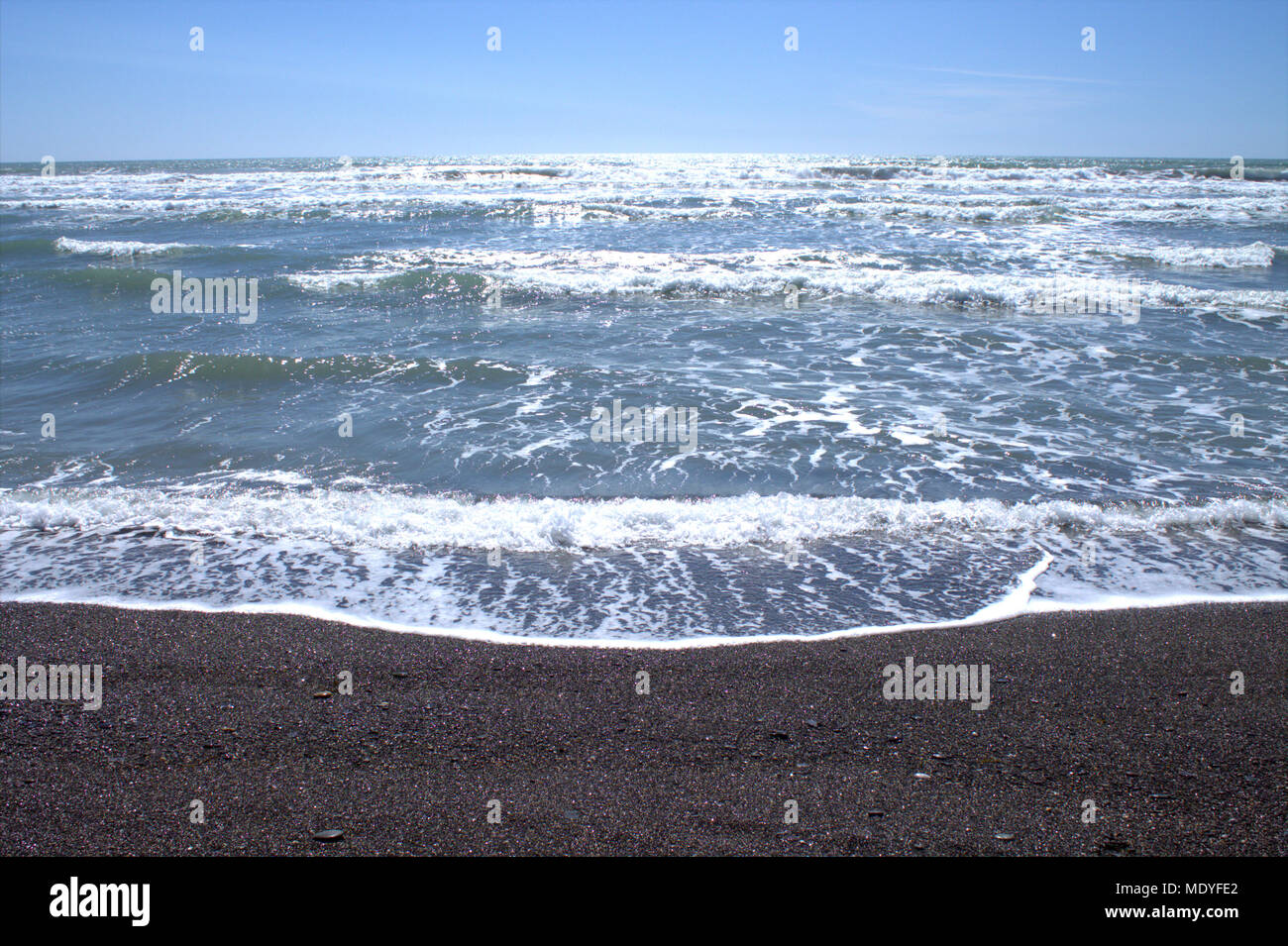 Atlantik Wellen auf eine irische Kieselstrand mit der nachmittäglichen Sonne funkeln im Wave-Kappen. West Cork Beach Holiday Destination. Stockfoto