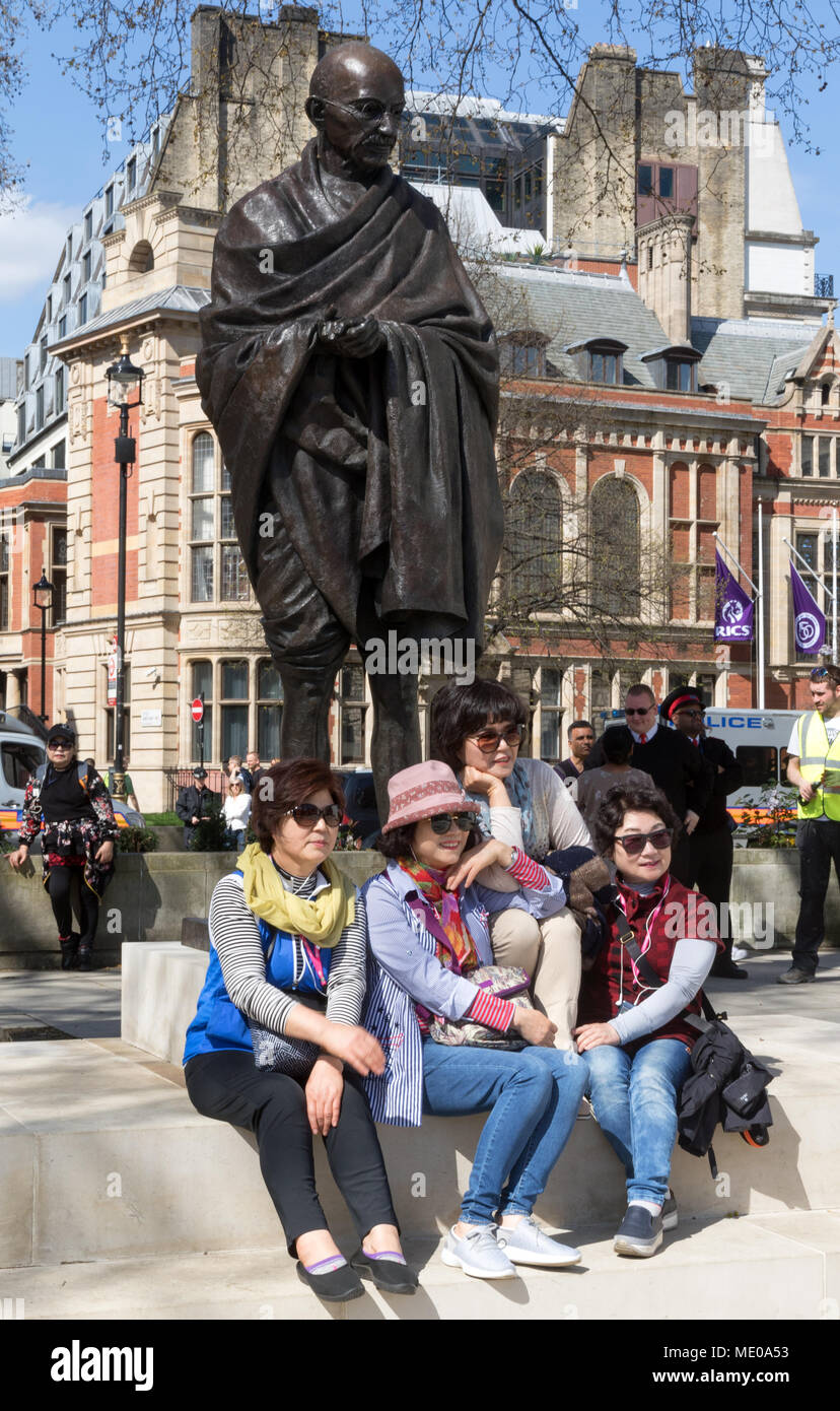 Japanische Touristen für Fotografie an der Mahatma Gandhi Statue in London's Parliament Square posiert Stockfoto