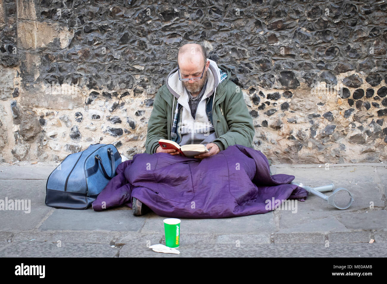 Ein obdachloser Mann sitzt auf dem Bürgersteig Lesung mit Schale bereit, Geld spenden in Canterbury zu sammeln Stockfoto