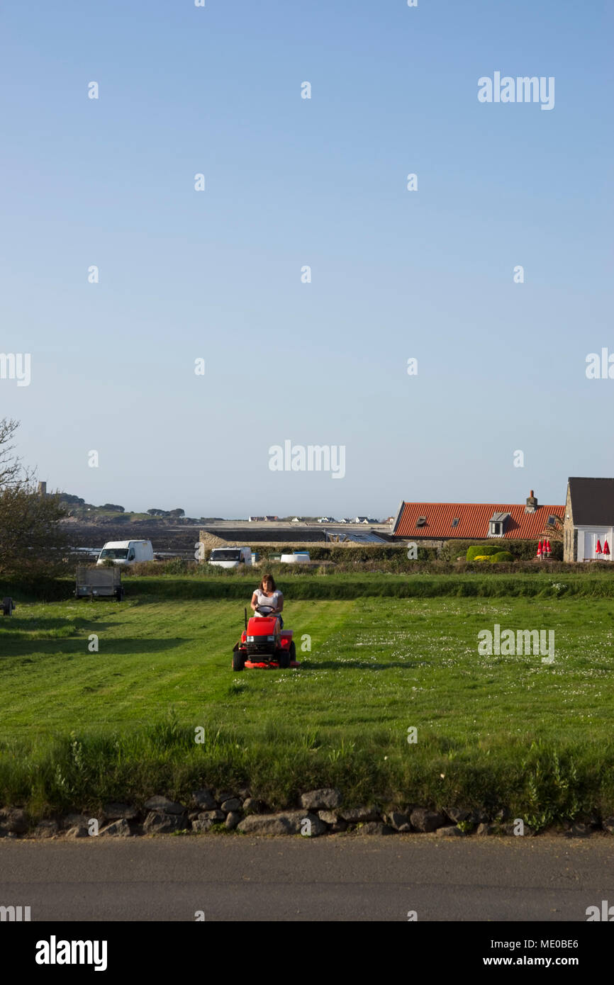 Frau auf motorisierten Rasenmäher Schneiden von Gras auf großem Grundstück. Stockfoto