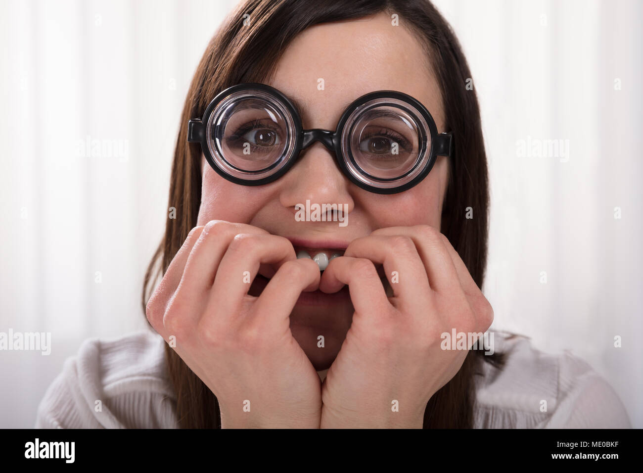 Betrachtet Nerd Frau tragen Brillen beißen Ihre Fingernägel Stockfoto