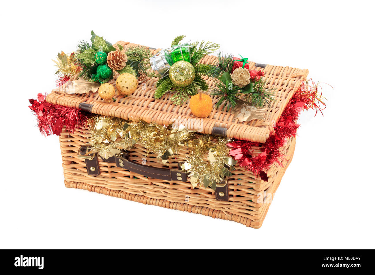 Geschlossen Weidenkorb überfüllt mit roten und goldenen Lametta mit Weihnachtsschmuck ruht auf dem Deckel Stockfoto