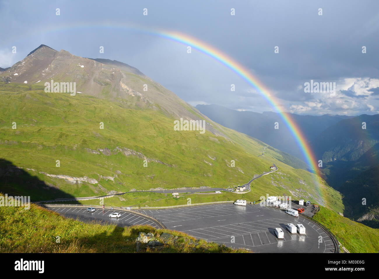 Regenbogen über Berglandschaft mit Parkplatz bei Kaiser Franz Josefs Hohe im Nationalpark Hohe Tauern in Kärnten, Österreich Stockfoto