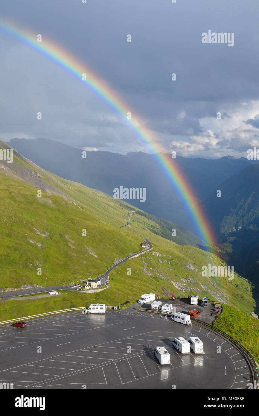 Regenbogen über Berglandschaft mit Parkplatz bei Kaiser Franz Josefs Hohe im Nationalpark Hohe Tauern in Kärnten, Österreich Stockfoto