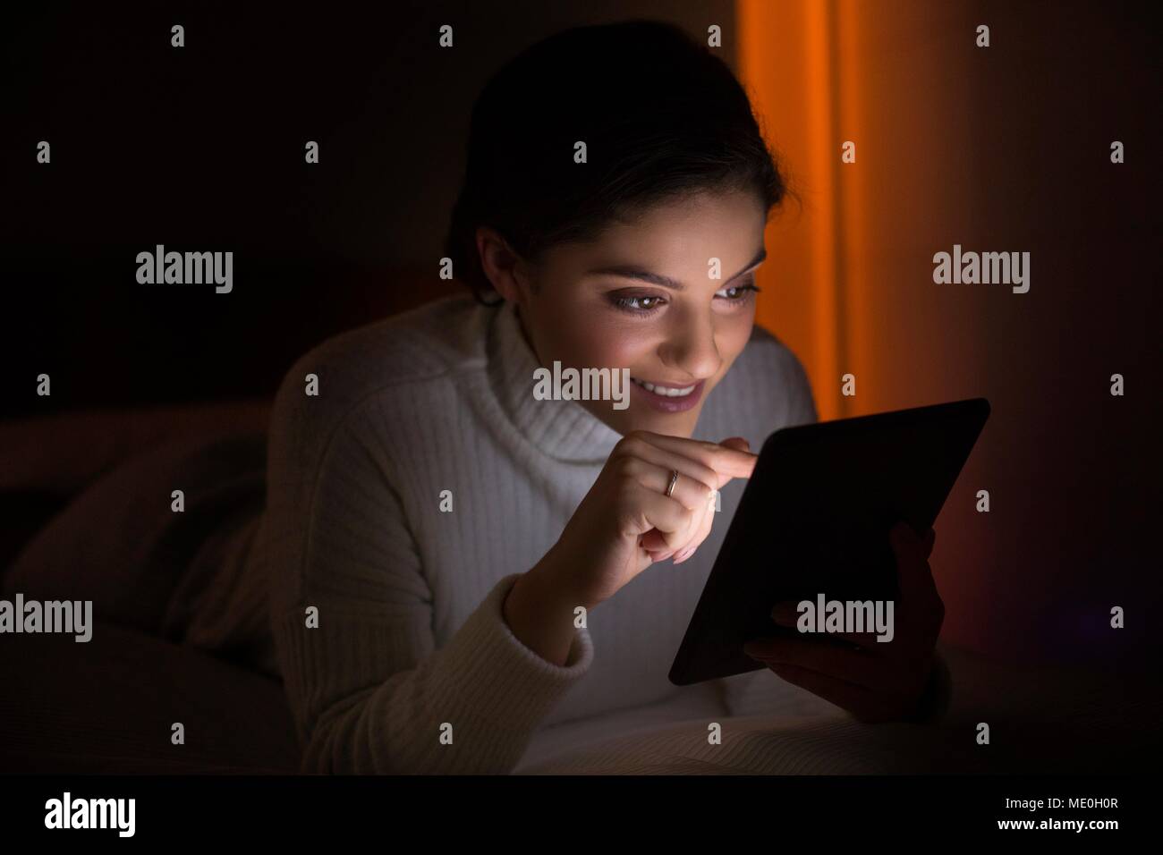 Junge Frau mit digitalen Tablette im dunklen Zimmer. Stockfoto