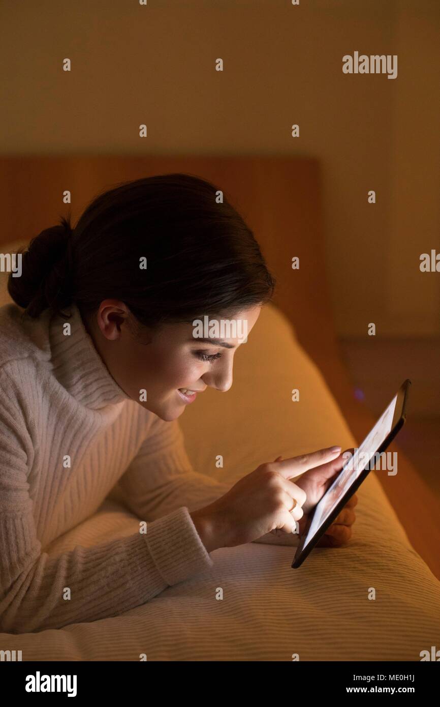 Junge Frau liegend auf Bett mit digitalen Tablet. Stockfoto