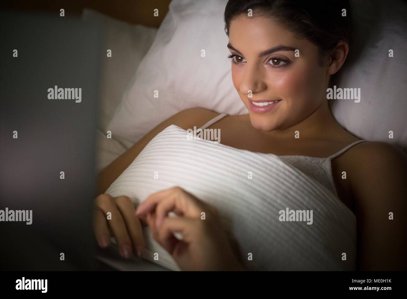 Junge Frau im Bett beobachten Laptop liegen. Stockfoto
