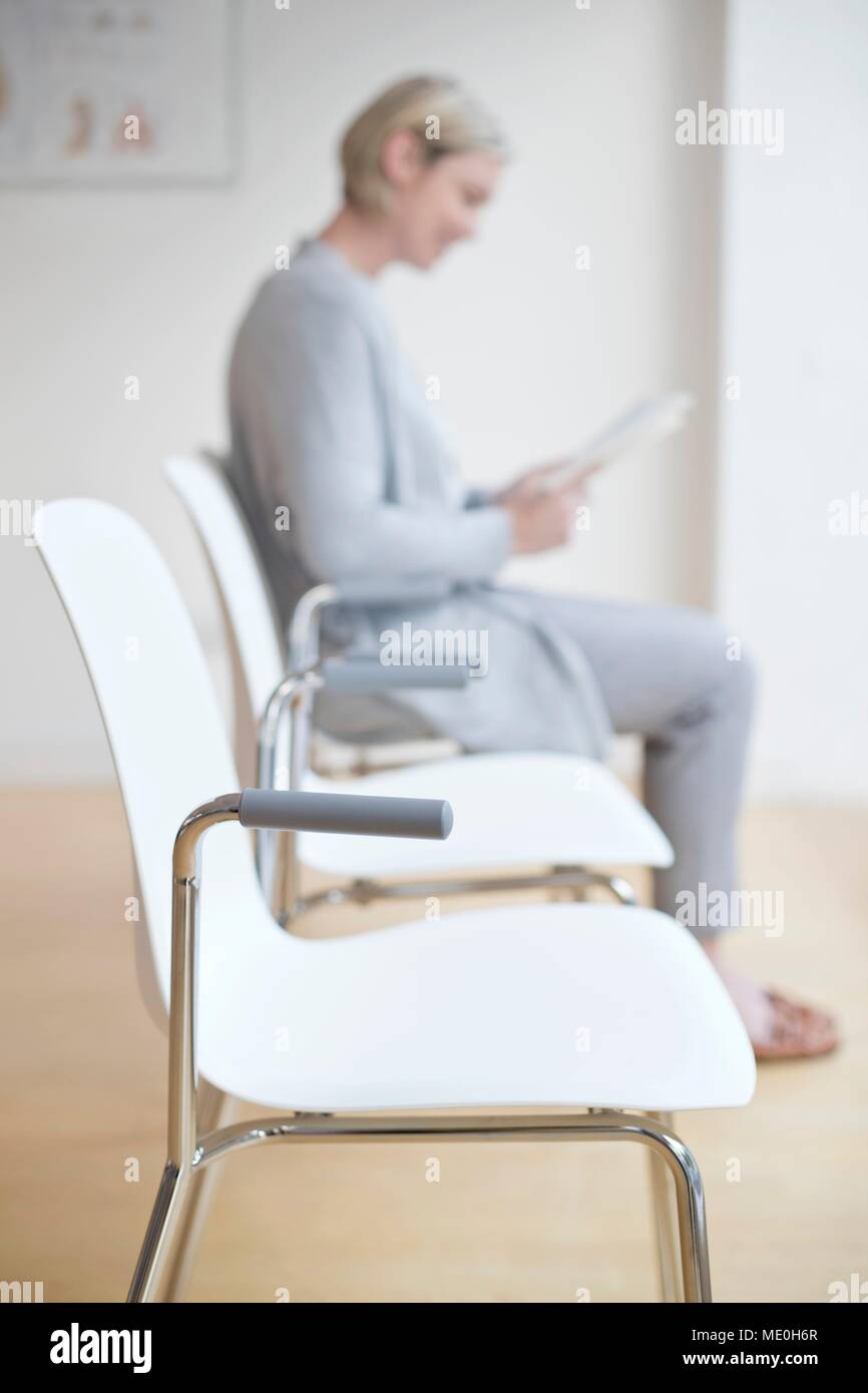 Frau sitzt in der Arzt, der Warteraum lesen Magazin. Stockfoto