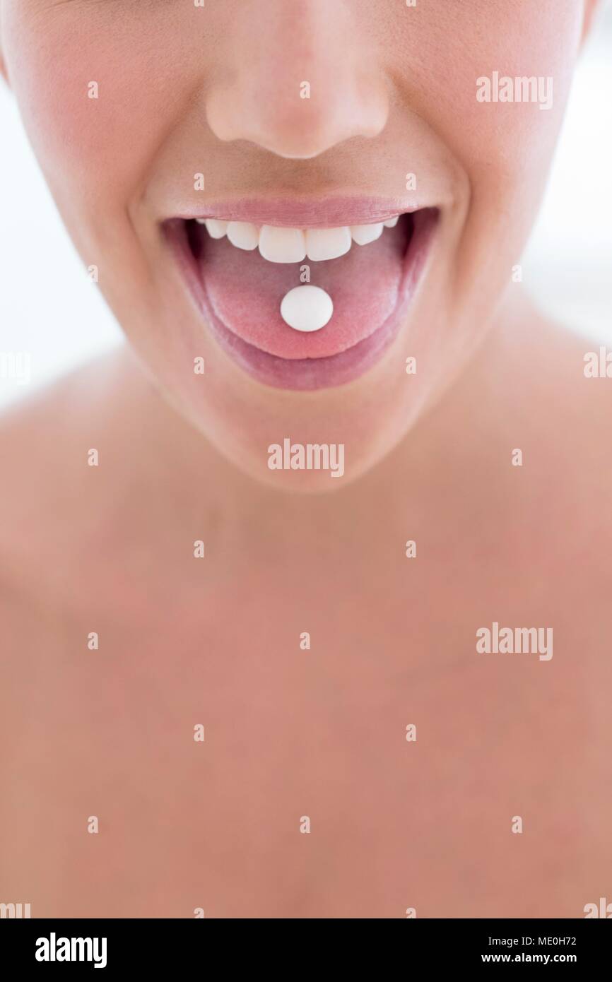 Junge Frau mit Pille auf der Zunge. Stockfoto