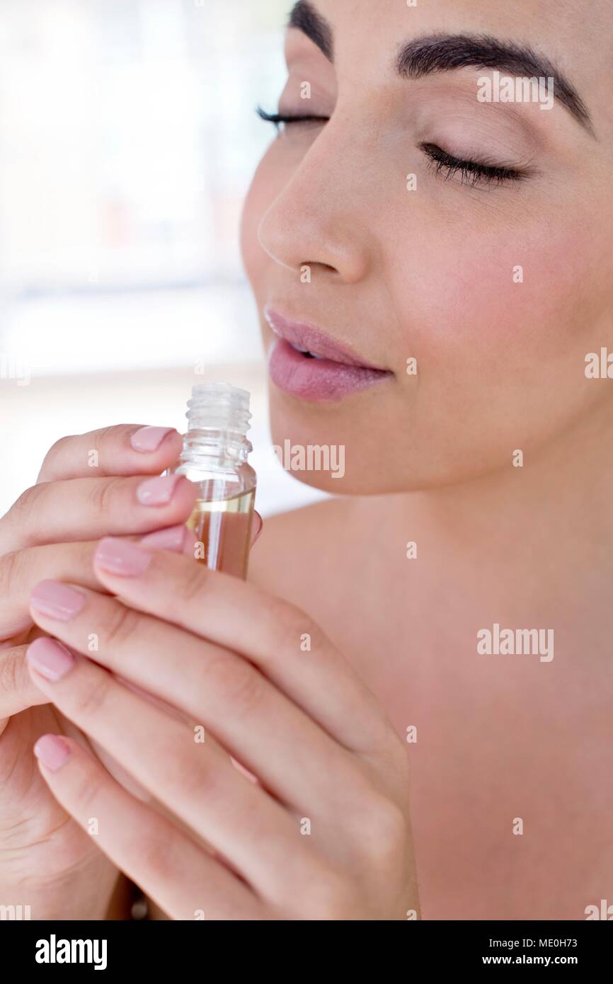 Junge Frau riechende Flüssigkeit in kleinen Fläschchen. Stockfoto