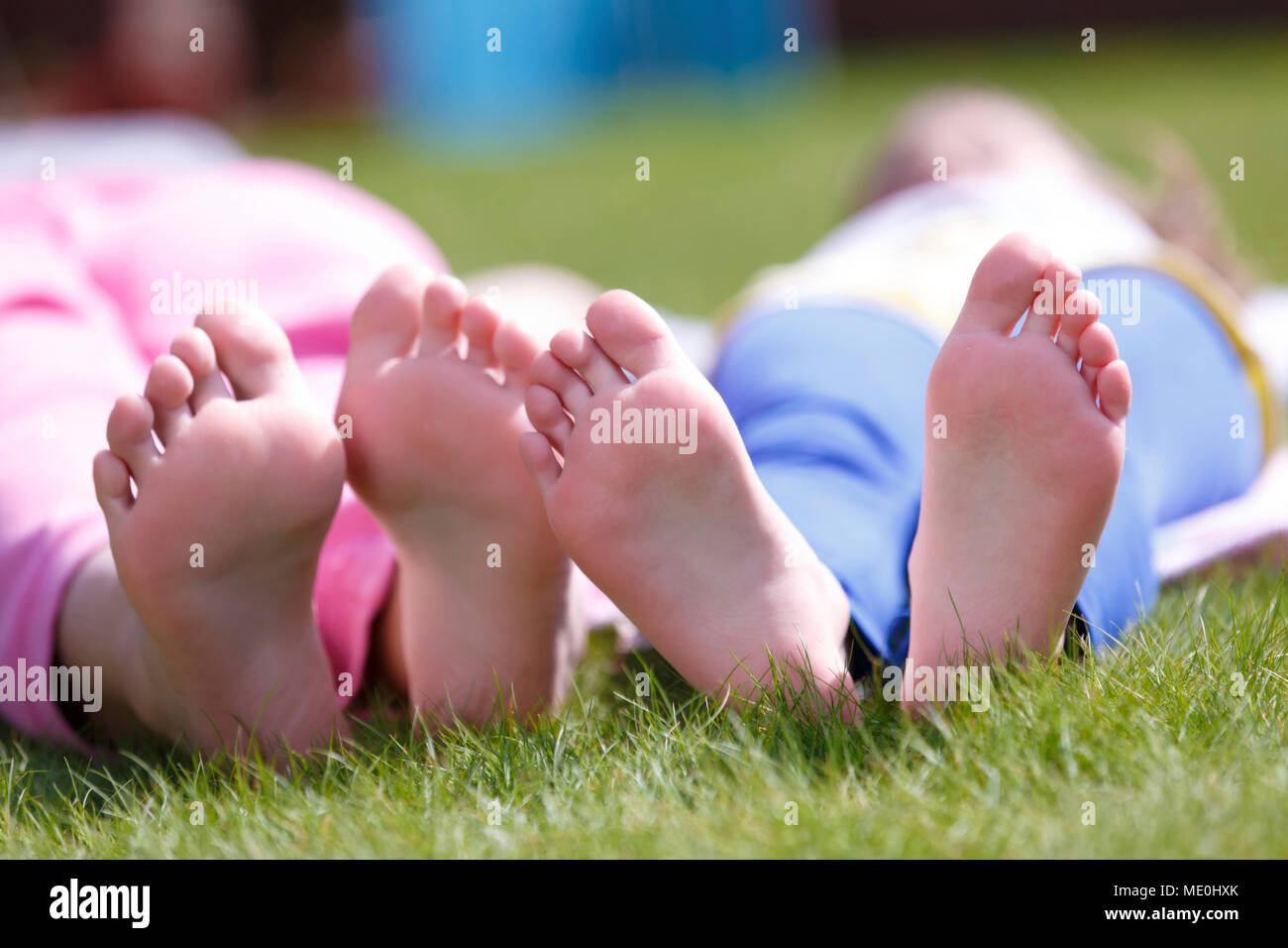 Nackte Girls' Füße auf Gras. Stockfoto