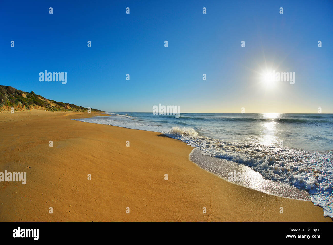 Surfen brechen auf der Küstenlinie von Ninety Mile Beach Paradise Beach mit der Sonne über den Ozean in Victoria, Australien, glänzend Stockfoto