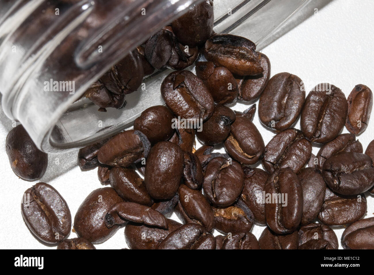 Dunkel geröstete Kaffeebohnen aus Glas auf weißem Hintergrund Stockfoto