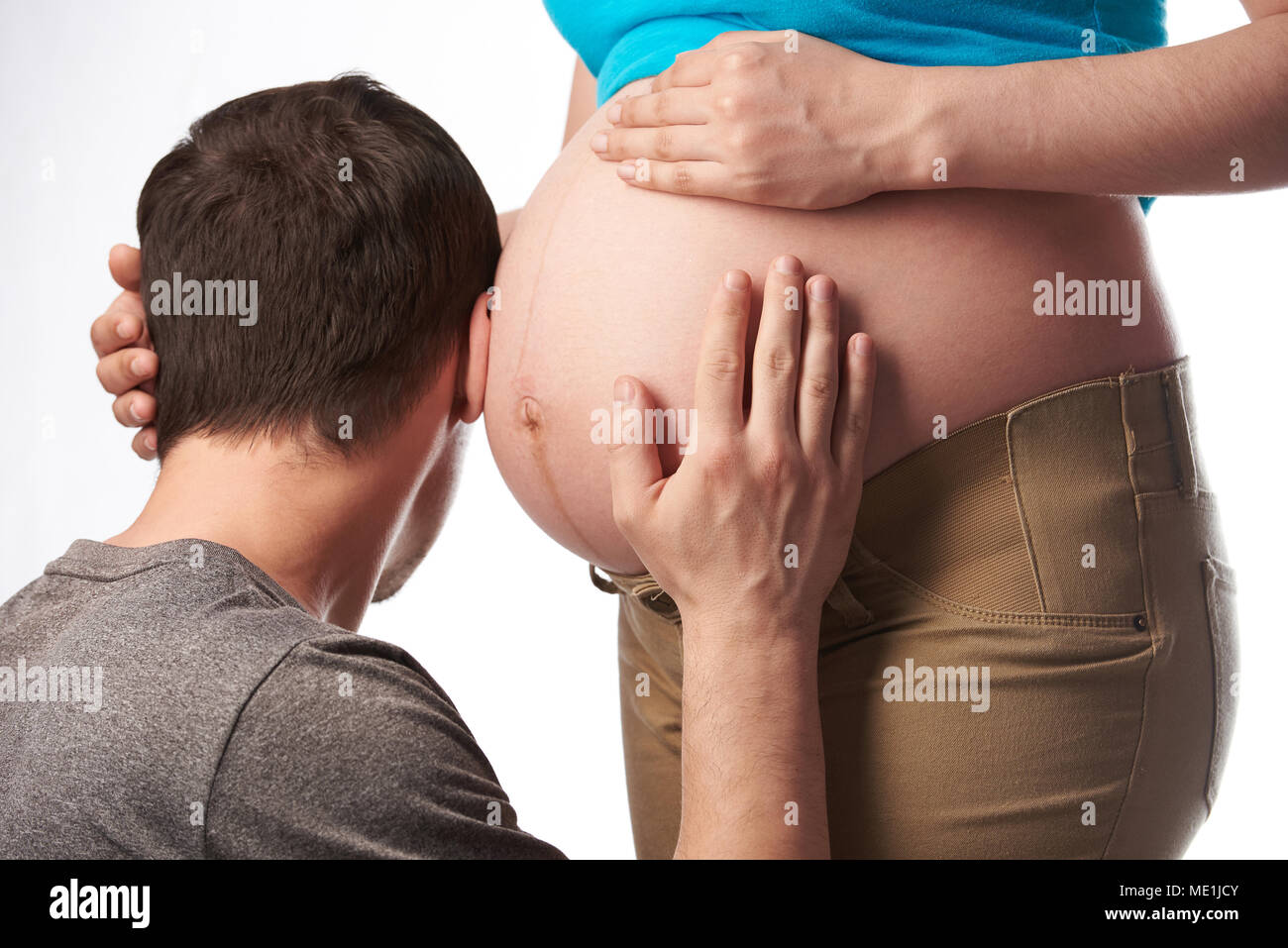 Man Ohr schwangeren Bauch auf weißem Hintergrund Stockfoto