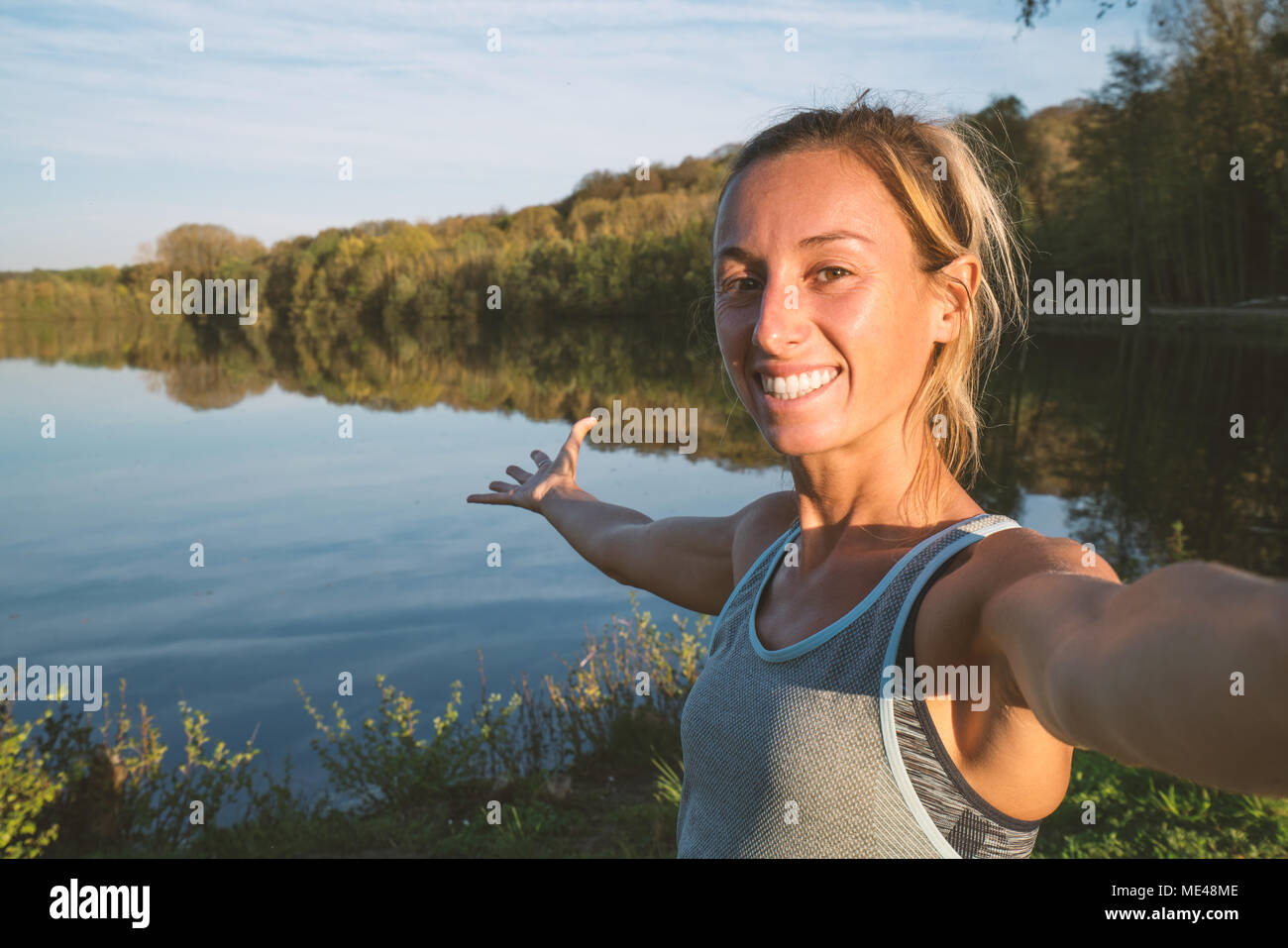 Junge Frau nimmt eine Selfie portrait am See bei Sonnenuntergang, schöne Reflexion. Menschen reisen, Umwelt teilen Konzept. In Frankreich, Europa Schuß Stockfoto
