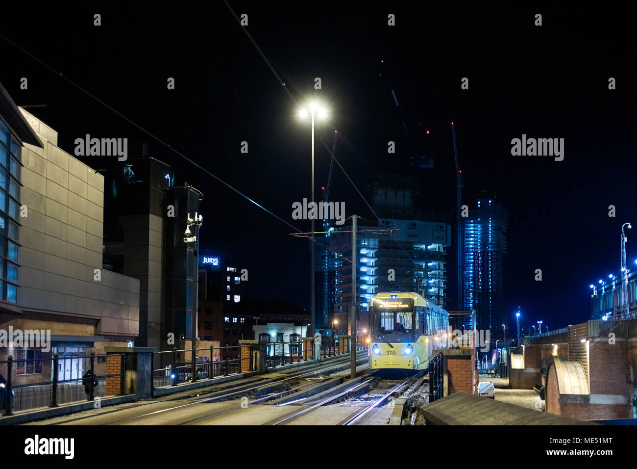 Straßenbahn nach Rochdale in das Zentrum von Manchester City an nigth mit hohen Gebäuden und Baukräne im Hintergrund kommen bei Nacht Stockfoto