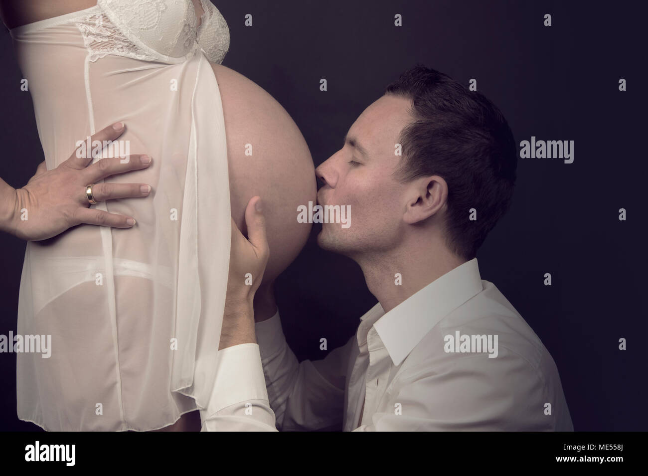 Den werdenden Vater Küsse zärtlich den schwangeren Bauch seiner Frau Stockfoto