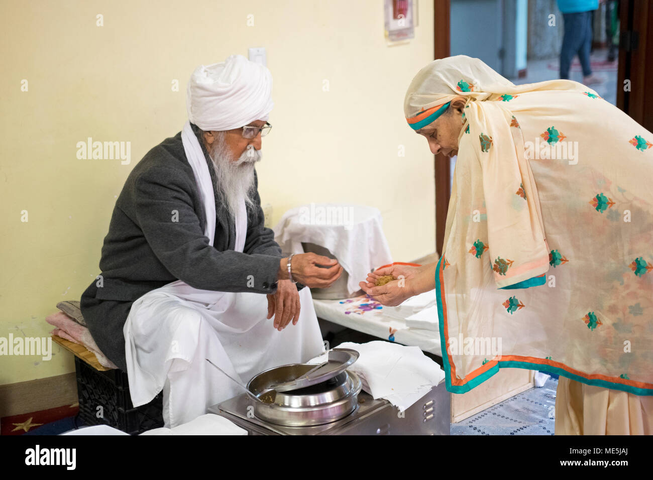 Ein Verehrer im Sikh Cultural Center erhält eine Handvoll prasad, eine süße Gratina, die allen Besuchern eines Tempels gegeben wird. In Richmond Hill, Queens, Stockfoto