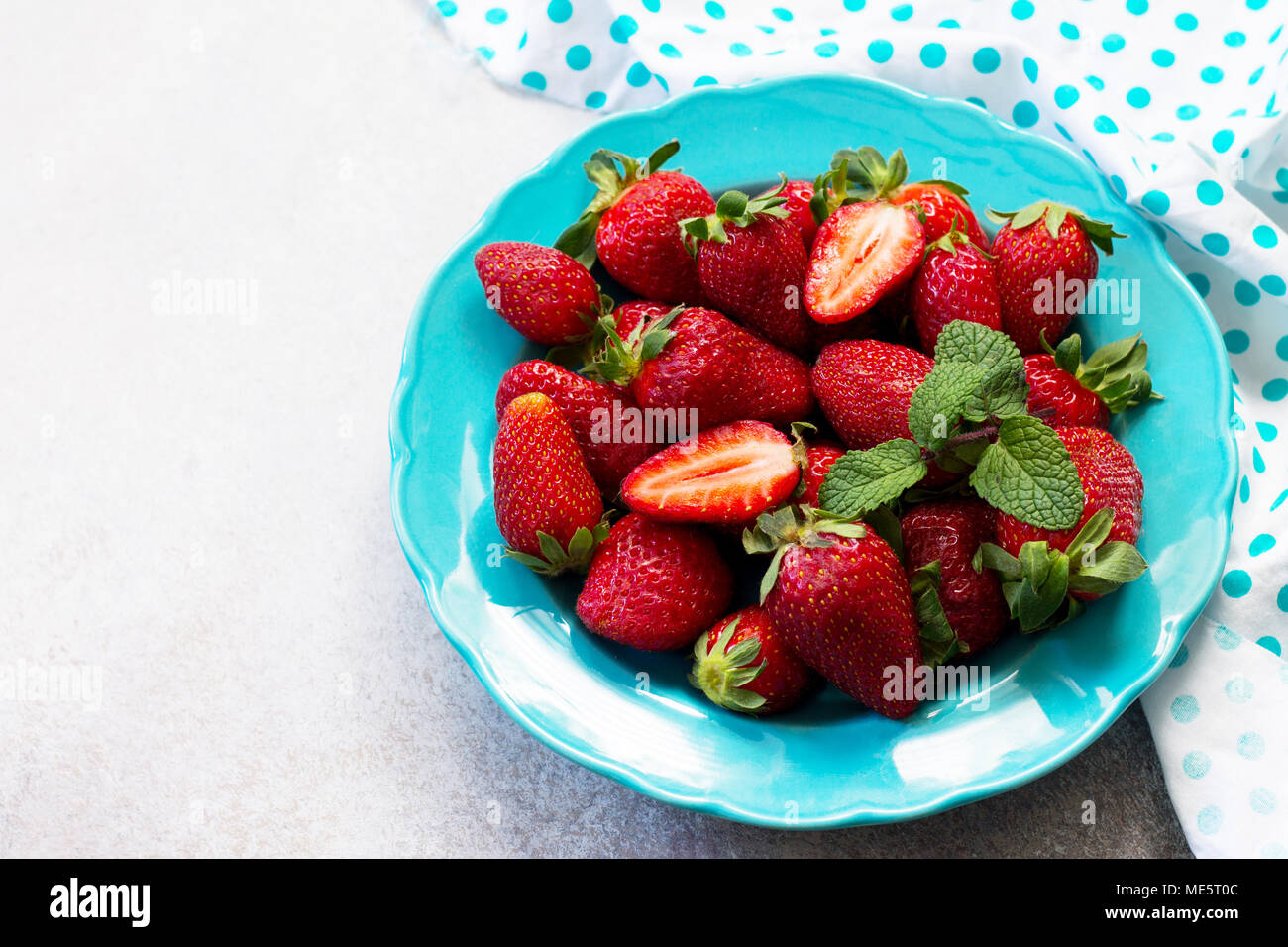 Beeren für frische Erdbeeren in einem blauen Keramikplatte auf grauem Stein oder Schiefer Hintergrund. Das Konzept der Ernährung Gesundheit oder Entgiftung. Stockfoto