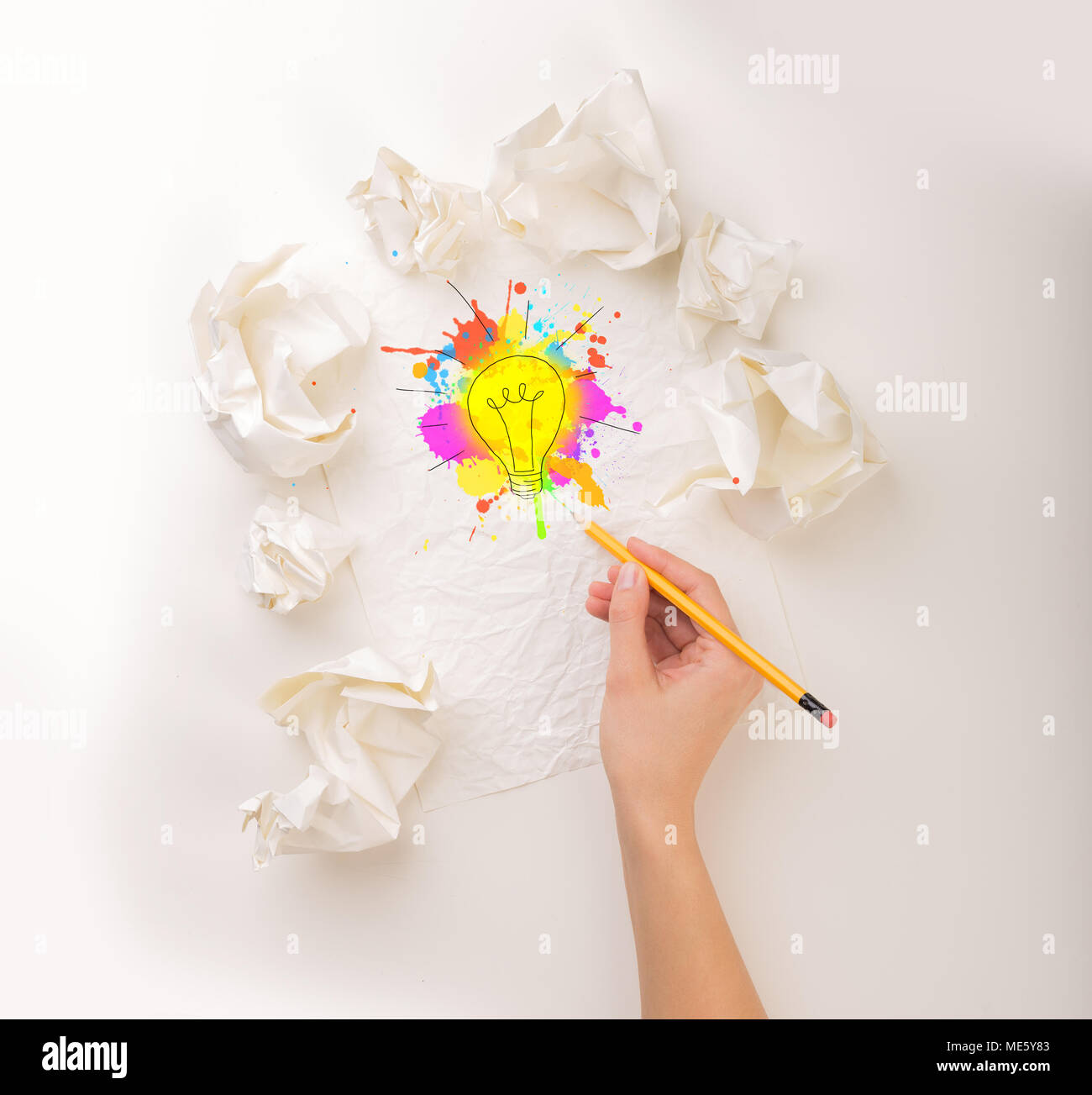 Weibliche Hand neben ein paar zerknittertes Papier Kugeln zeichnen ein farbenfrohes Glühbirne Stockfoto