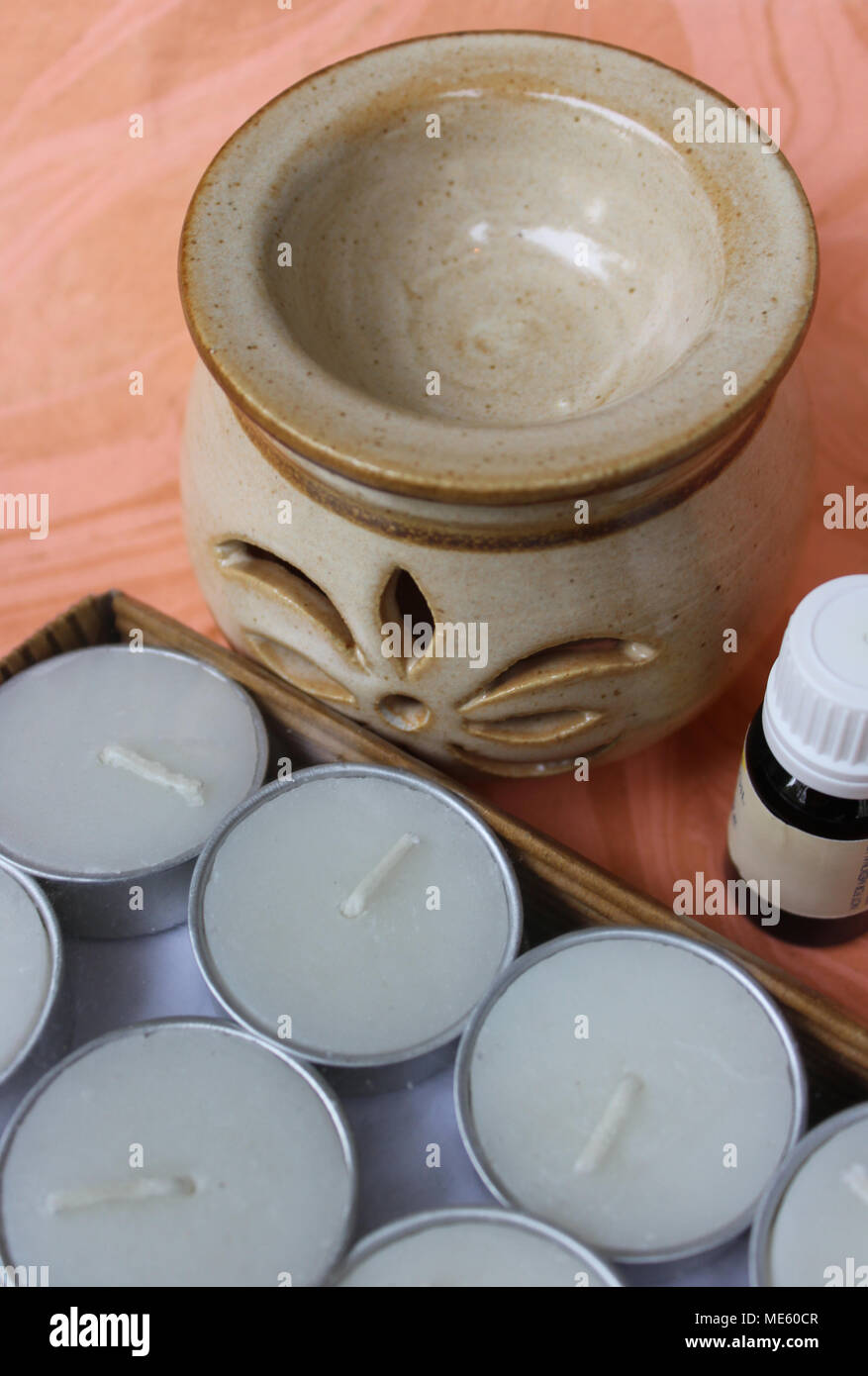 Keramikdiffusor, Packung Teelichter und Flasche natürliche ätherische Öl auf handgeschöpftem Papier gehalten Stockfoto