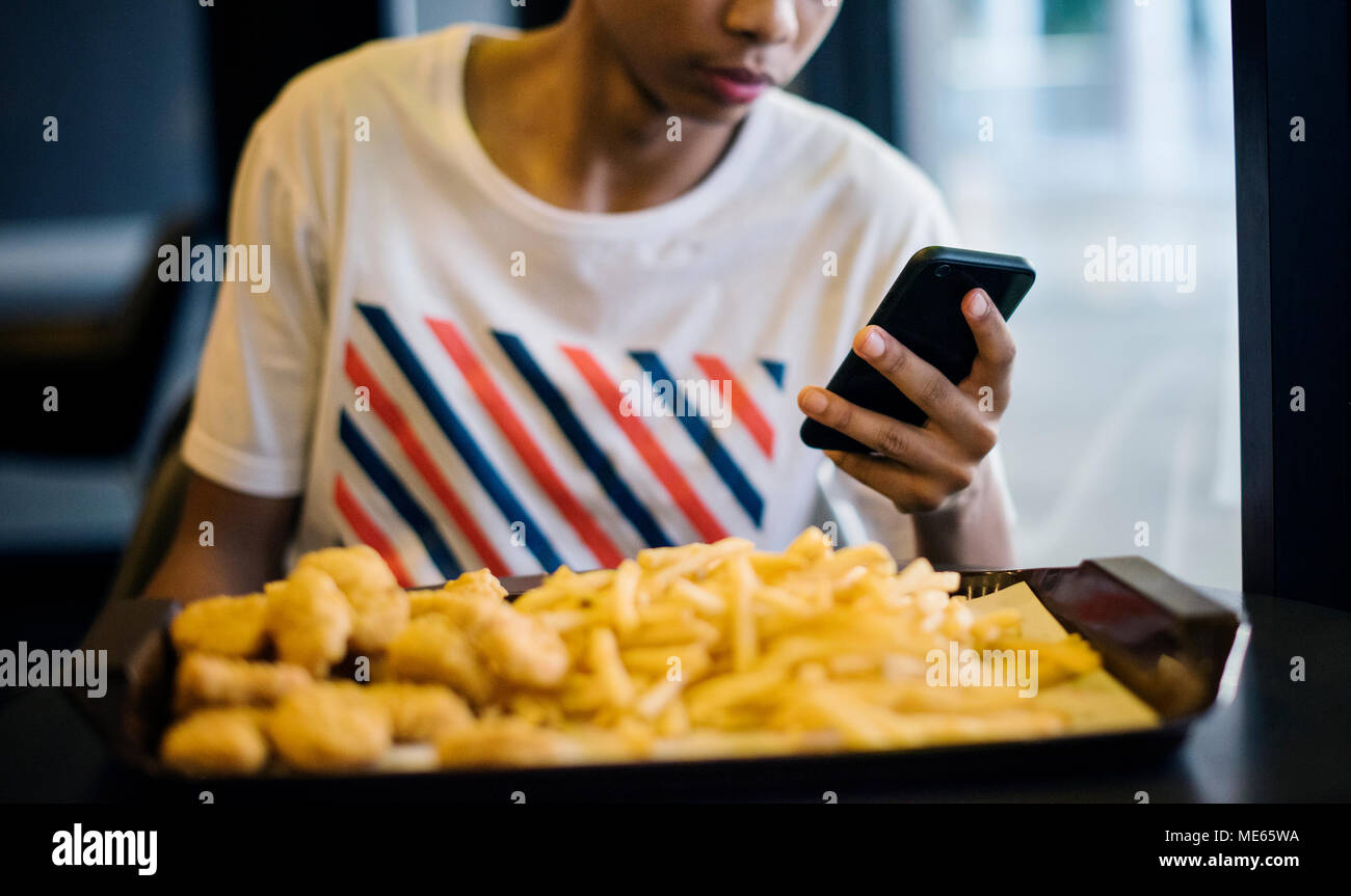 Nahaufnahme von Teenager mit einem Smartphone Essen Pommes frites Jugend Kultur Konzept Stockfoto