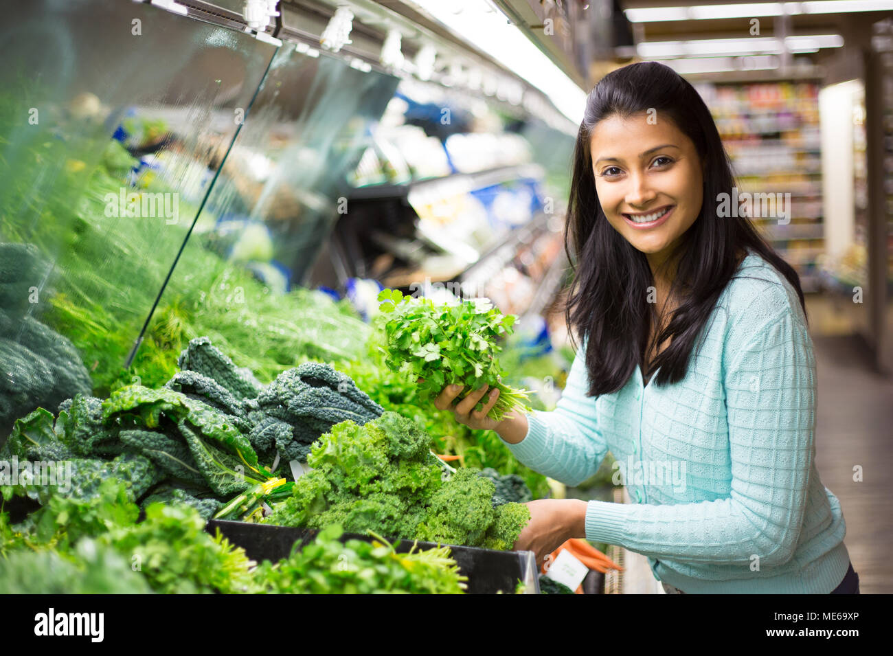 Closeup Portrait, schöne, hübsche junge Frau in Pullover, Abholung, Wahl grünes Blattgemüse in Lebensmittelgeschäft Stockfoto