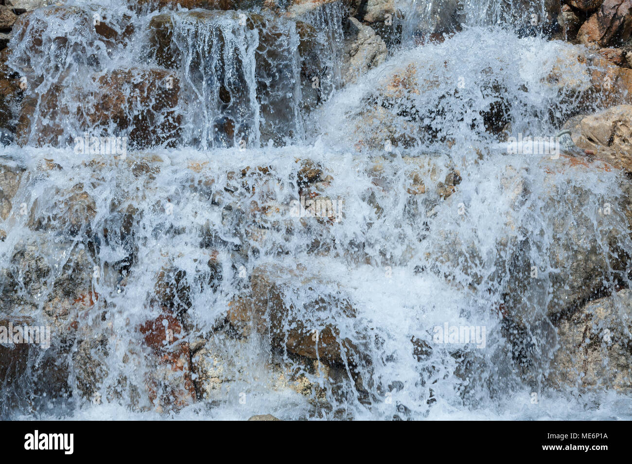 Das Wasser spritzt auf den Felsen Stockfoto