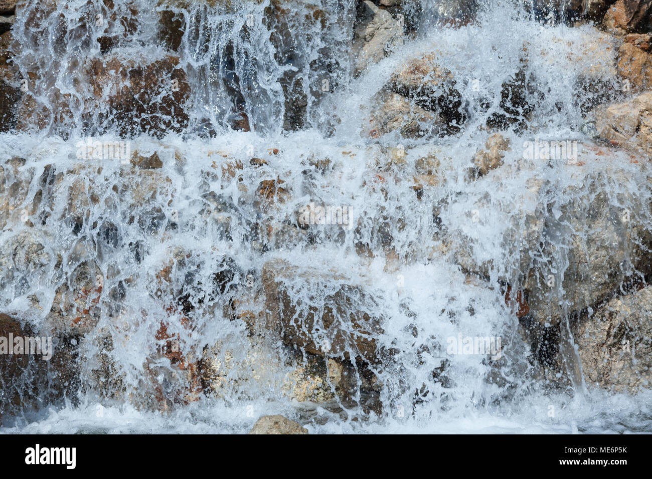 Das Wasser spritzt auf den Felsen Stockfoto