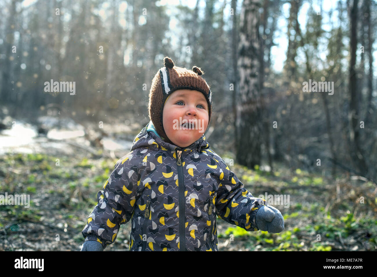 Das Kind spielt emotional mit einem Zweig, Zauber und Charme in den Wald. Wald ohne Blätter im Frühling oder Herbst. Stockfoto