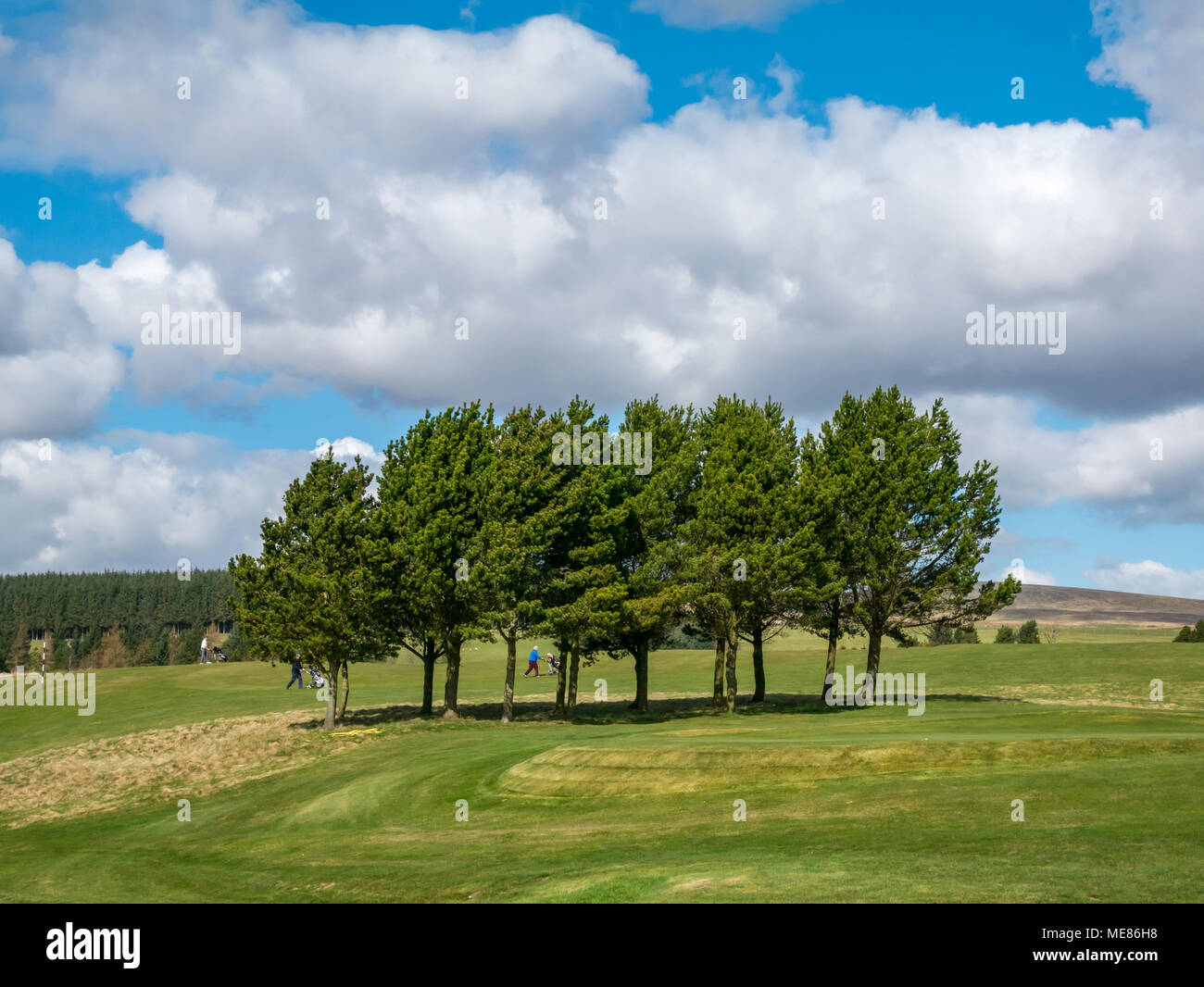 West Linton, Scottish Borders, Schottland, Vereinigtes Königreich, 21. April 2018. Frühlingssonne bei West Linton Golfplatz mit Golfspieler zu Fuß über die Fahrrinne Stockfoto