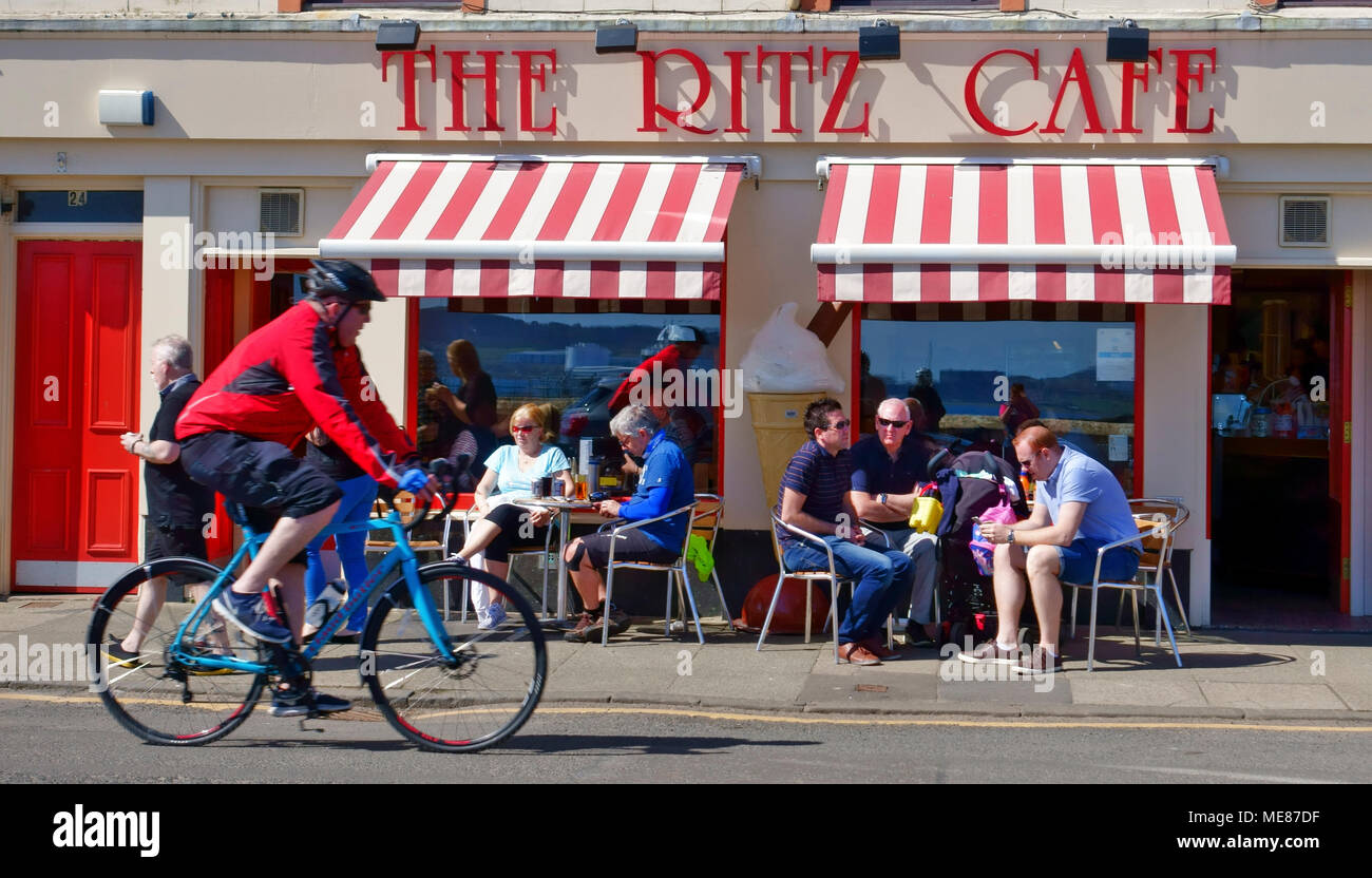 Schottland, Großbritannien. 21. April 2018. Menschen außerhalb des Ritz Cafe in Millport, Isle of Cumbrae in Ayrshire, Schottland sitzend, genießen die April Sonnenschein. Das Ritz Cafe, ein im Stil der 50er Eisdiele mit Tag beliebt ist, Ausflügler und hat auf millport's Waterfront seit über 100 Jahren. Credit: PictureScotland/Alamy leben Nachrichten Stockfoto