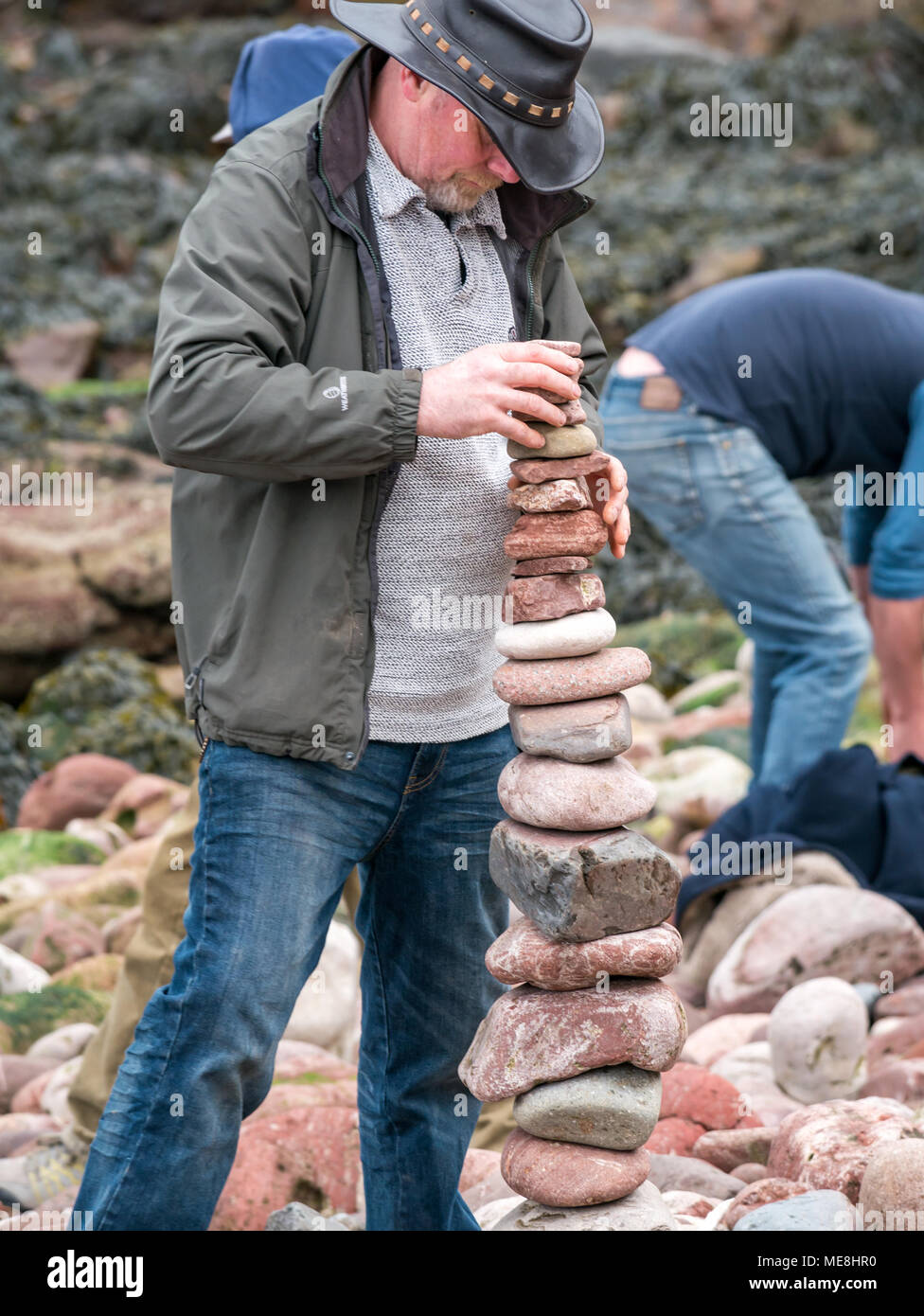 Dunbar, Schottland, 22. April 2018. Auge Cave Strand, Dunbar, East Lothian, Schottland, Vereinigtes Königreich, 22. April 2018. Der zweite Tag des zweiten Europäischen Stein stacking Meisterschaften an diesem Wochenende in Dunbar, von Dunbar Street Art Trail organisiert. Der erste Wettbewerb des Tages war die Anzahl der Steine in 20 Minuten. Der Gewinner ausgeglichen 29 Steine, etwas weniger als im letzten Jahr, gewann 32 Steine. Ein Konkurrent baut ein Stein Stapel Stockfoto