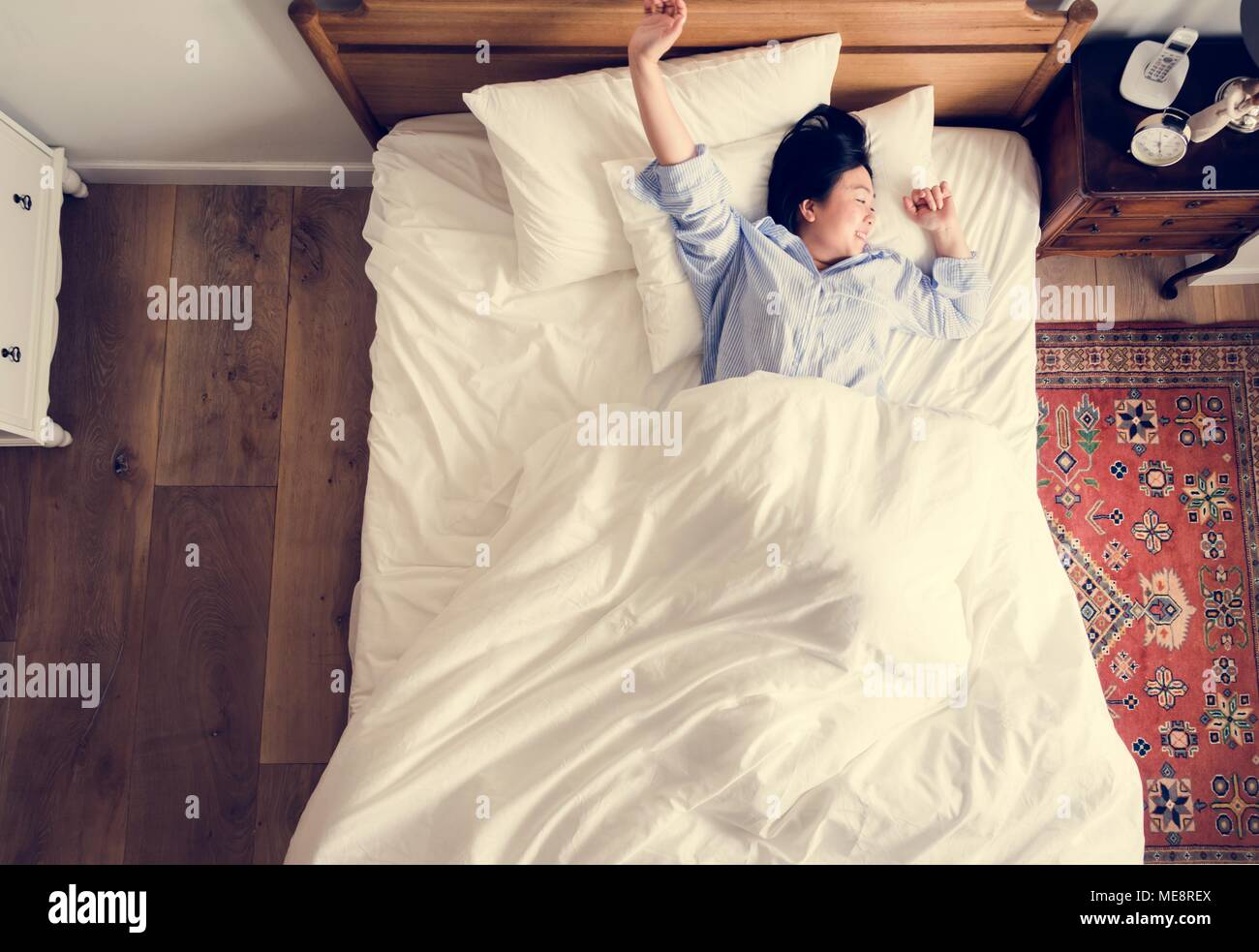 Asiatische Frau auf dem Bett Aufwachen am Morgen Stockfoto