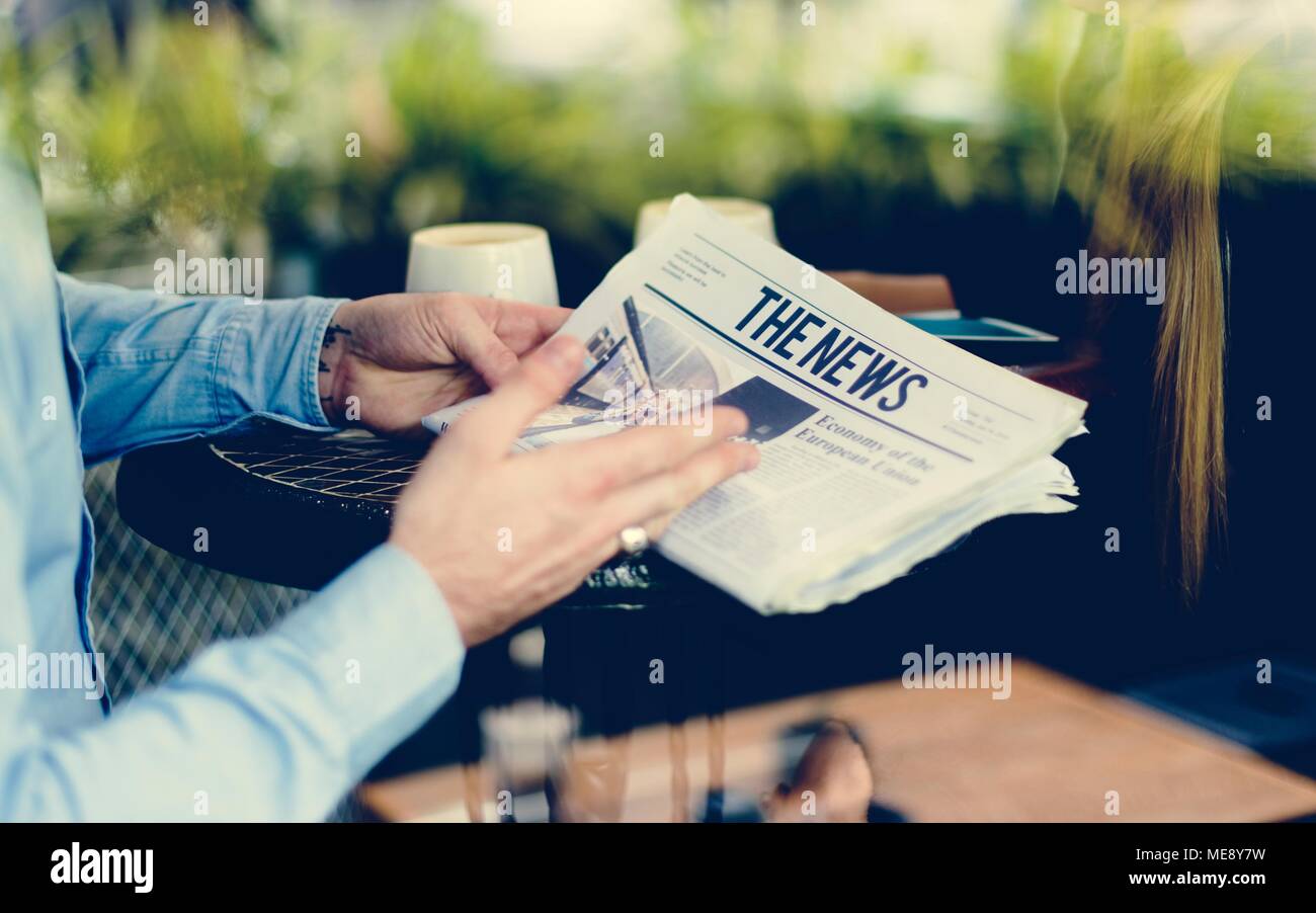 Hände halten eine Zeitung lesen im Café Stockfoto