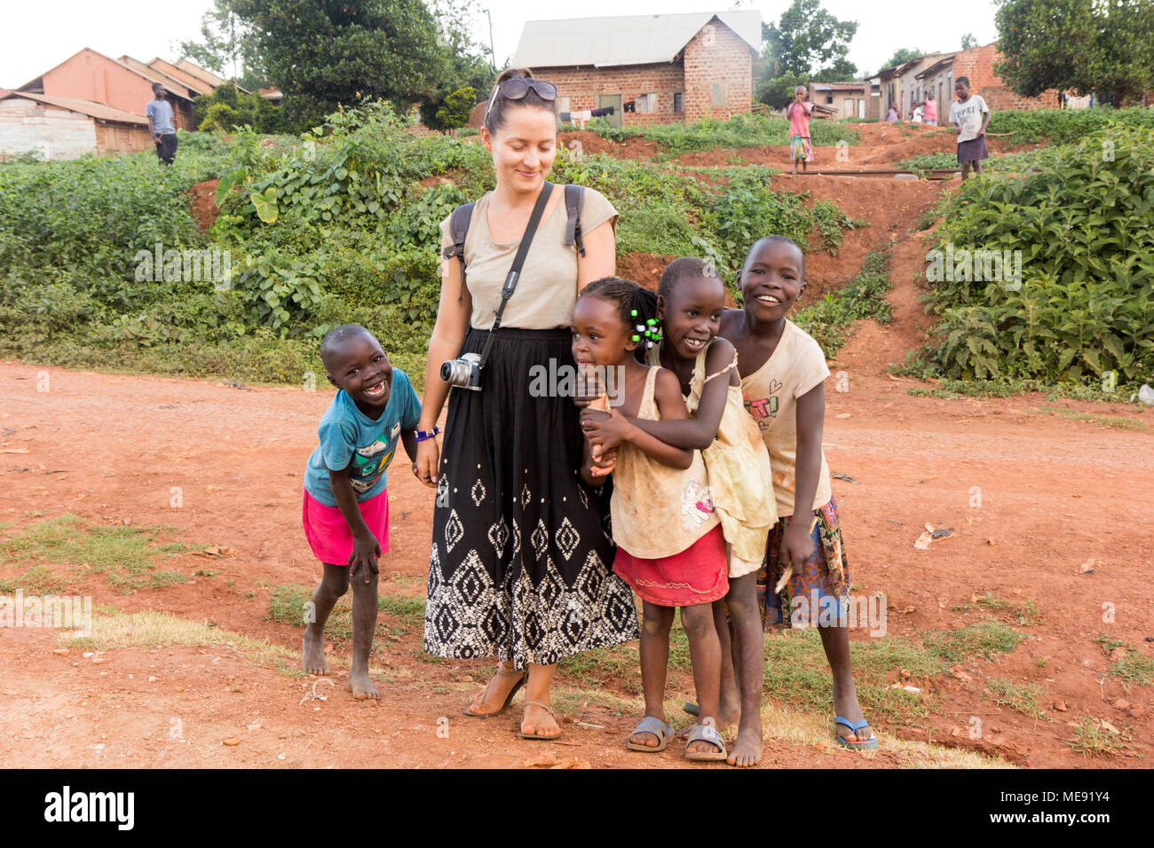 Lugazi, Uganda. 17. Mai 2017. Eine weiße Hautfarbe freiwillige ('mZungu' oder 'muzungu' lokal) Hände mit ugandischen Kinder in einer ländlichen Gegend. Stockfoto