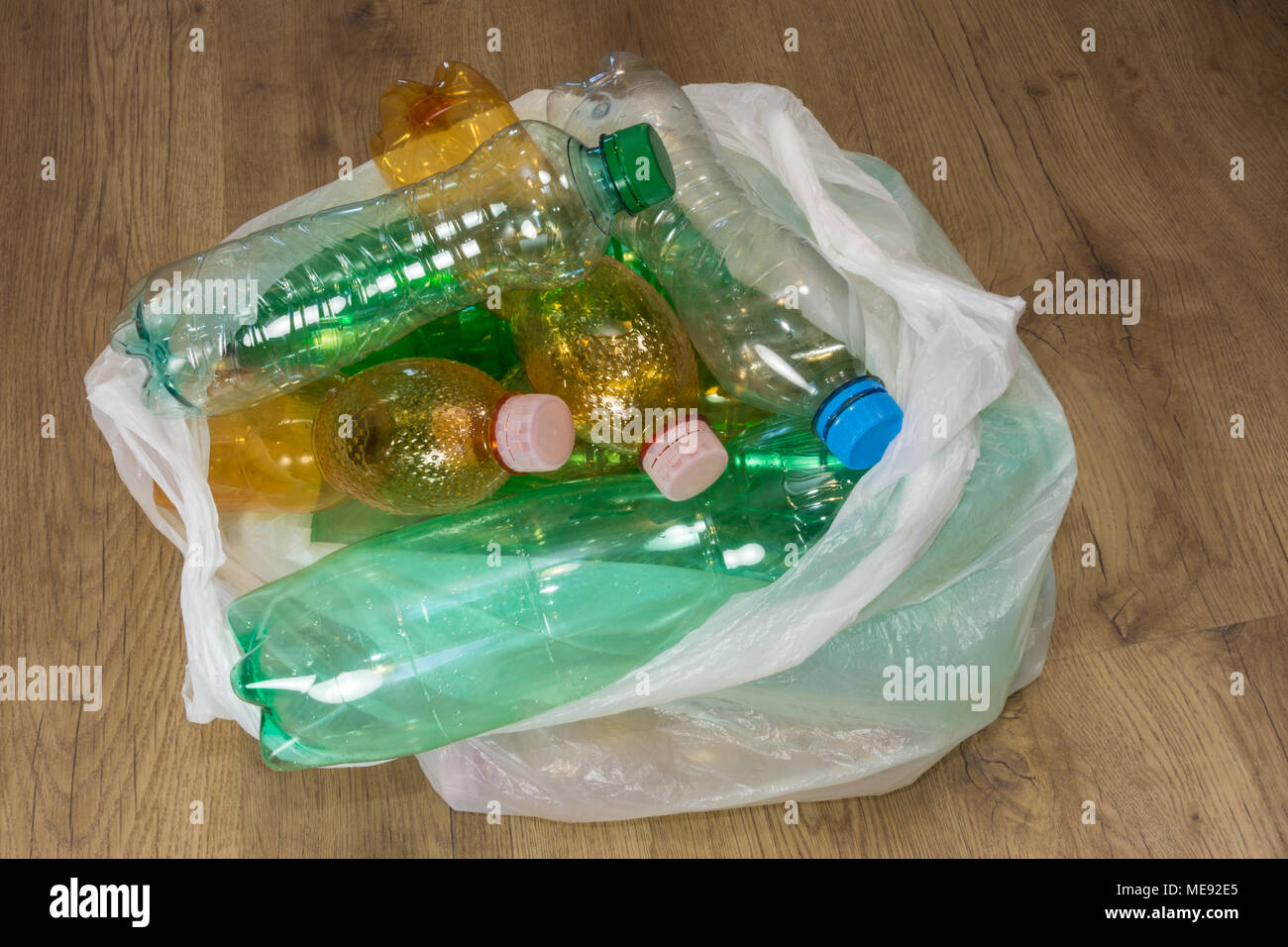 Leere PET-Flaschen auf Holz. Ökologische Trennung von Hausmüll entsorgt. Verwendete Kunststoff Abfälle in einer Tragetasche. Blick von oben. Stockfoto