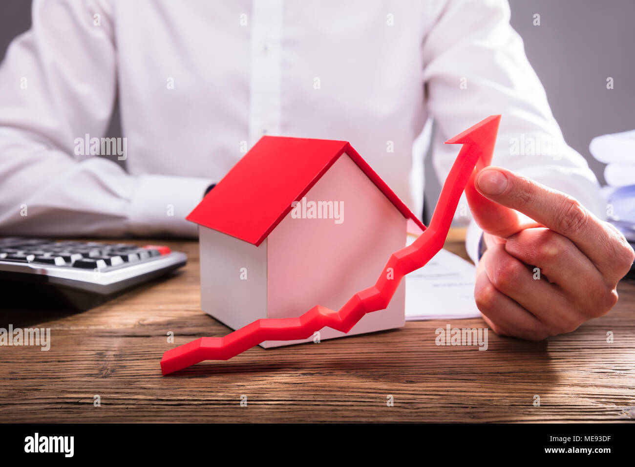 Der Unternehmer Hand mit roter Pfeil vor dem Haus Modell Stockfoto