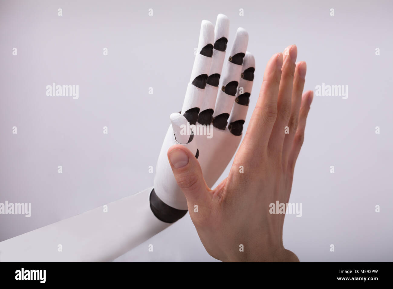 Roboter und Menschen mit hoher Fünf auf grauem Hintergrund Stockfoto