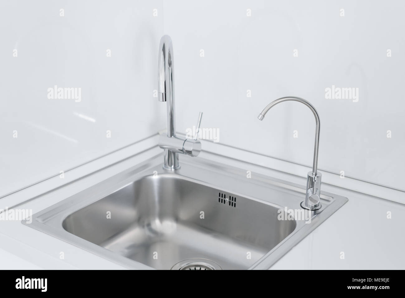 Metall chrom Waschbecken mit zwei Hähnen, schlicht und gefiltertes Wasser.  Fragment der modernen Küche mit Theke und einem Waschbecken. Detail des  Inneren Stockfotografie - Alamy