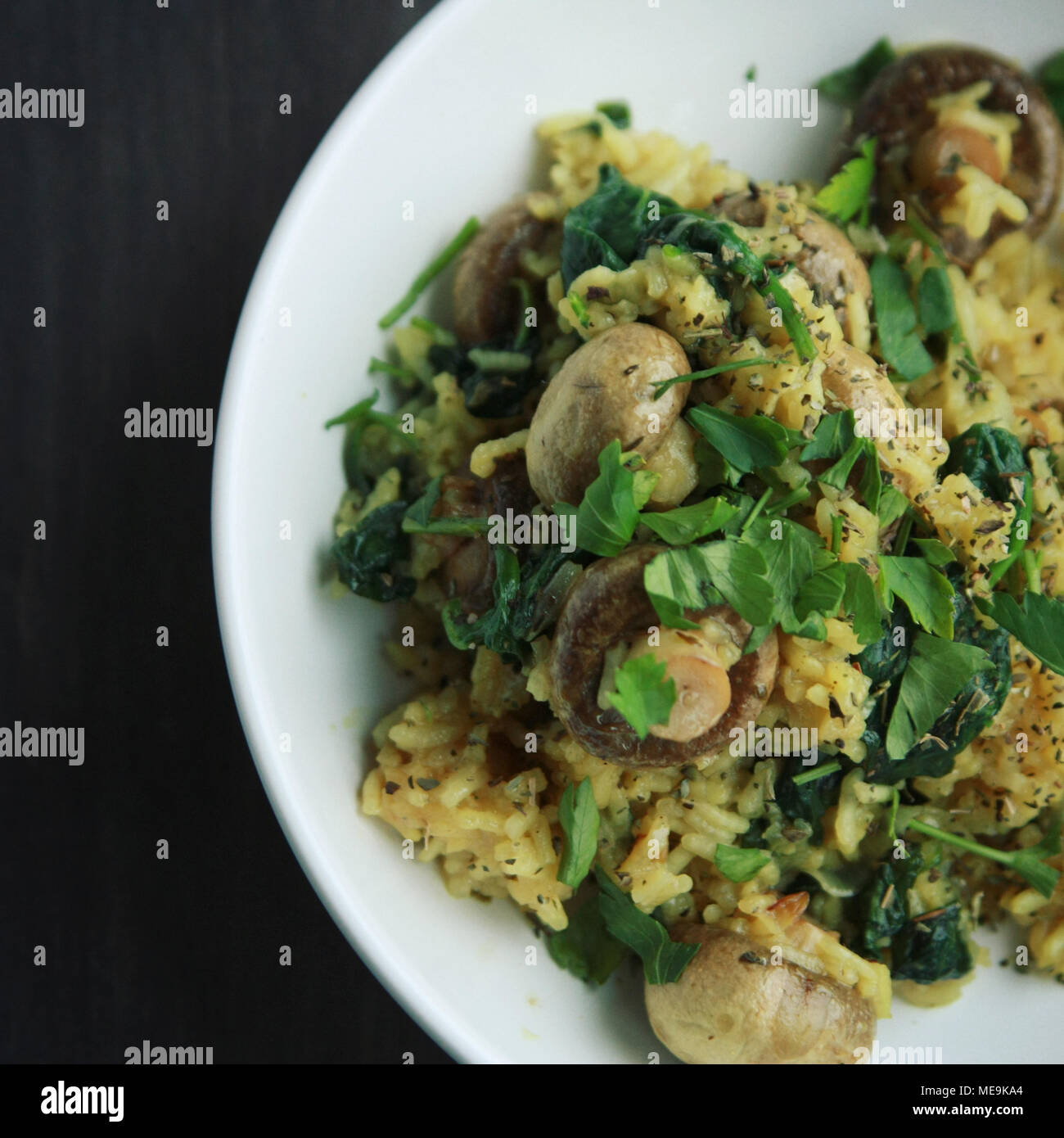 Gelber Reis mit Pilzen und Spinat. Vegane Gerichte. Europäische Küche. Vegetarische Gelbwurz Reis in die weiße Schüssel. Close Up. Getönten Bild. Stockfoto