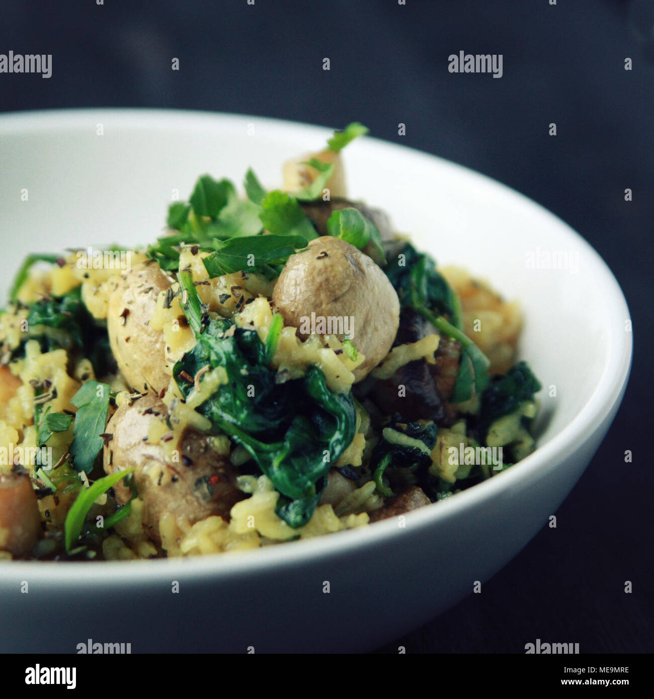 Gelber Reis mit Pilzen und Spinat. Vegane Gerichte. Europäische Küche. Vegetarische Gelbwurz Reis in die weiße Schüssel. Fleischlos. Getönten Foto. Stockfoto
