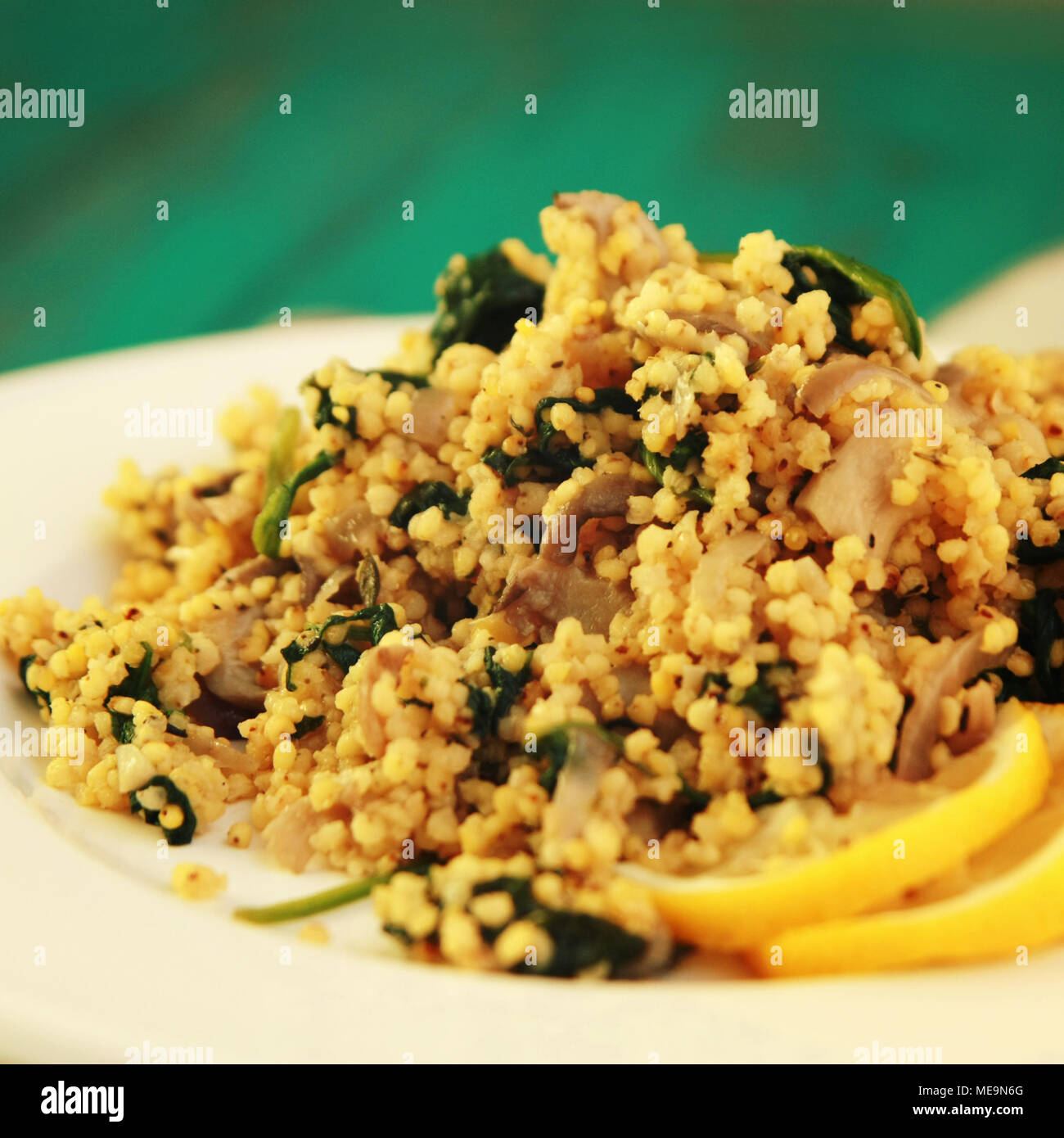 Hirse mit Pilzen und Spinat. Vegane Gerichte. Vegetarische couscous auf das runde weiße Platte. Close Up. Getönten Foto. Stockfoto