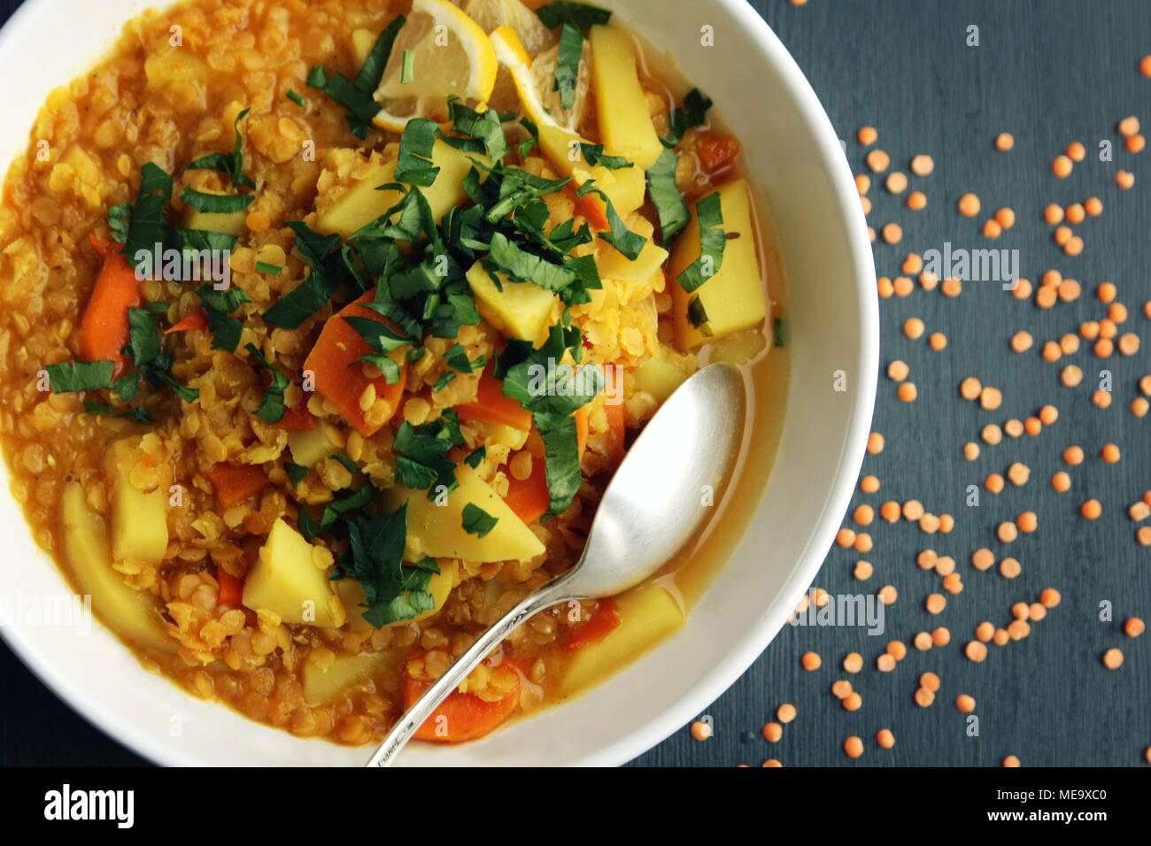 Rote Linsen Eintopf mit Kartoffeln, Karotten und Kurkuma. Getönten Foto. Gesundes Mittagessen auf der Runde weiße Platte. Bunte veganes Gericht mit Kartoffeln, Karotten und Tur Stockfoto