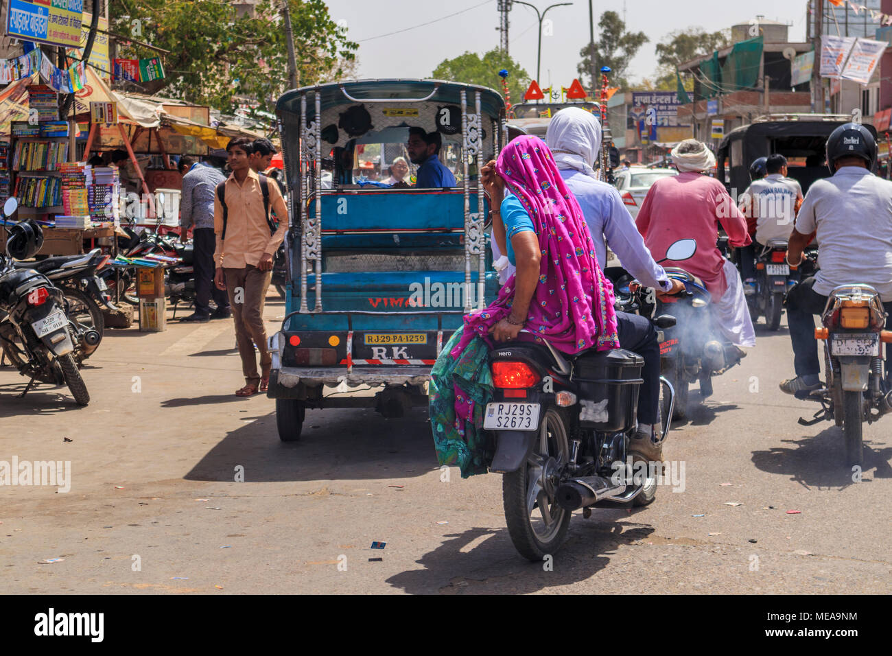 Straßenszene in Dausa, Rajasthan, Nordindien, eine lokale Frau reiten Sozius auf einem Motorrad mit typischen bunten lokalen Schleier Kopfschmuck und Kleidung Stockfoto