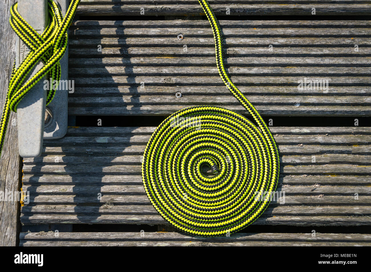 In der Nähe einer Spule der grünen Seil auf einer Holzterrasse mit einem Keil. Boot gefesselt auf einem Liegeplatz. Stockfoto