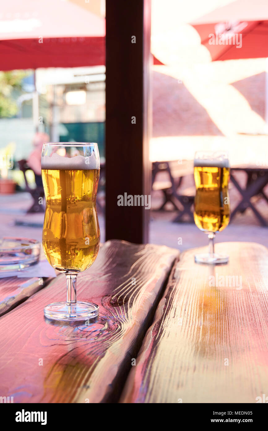 Zwei Gläser Bier auf dem Tisch zu stehen in einem Garten Pub auf ein Sommer sonnigen Tag mit einem unscharfen Hintergrund Stockfoto