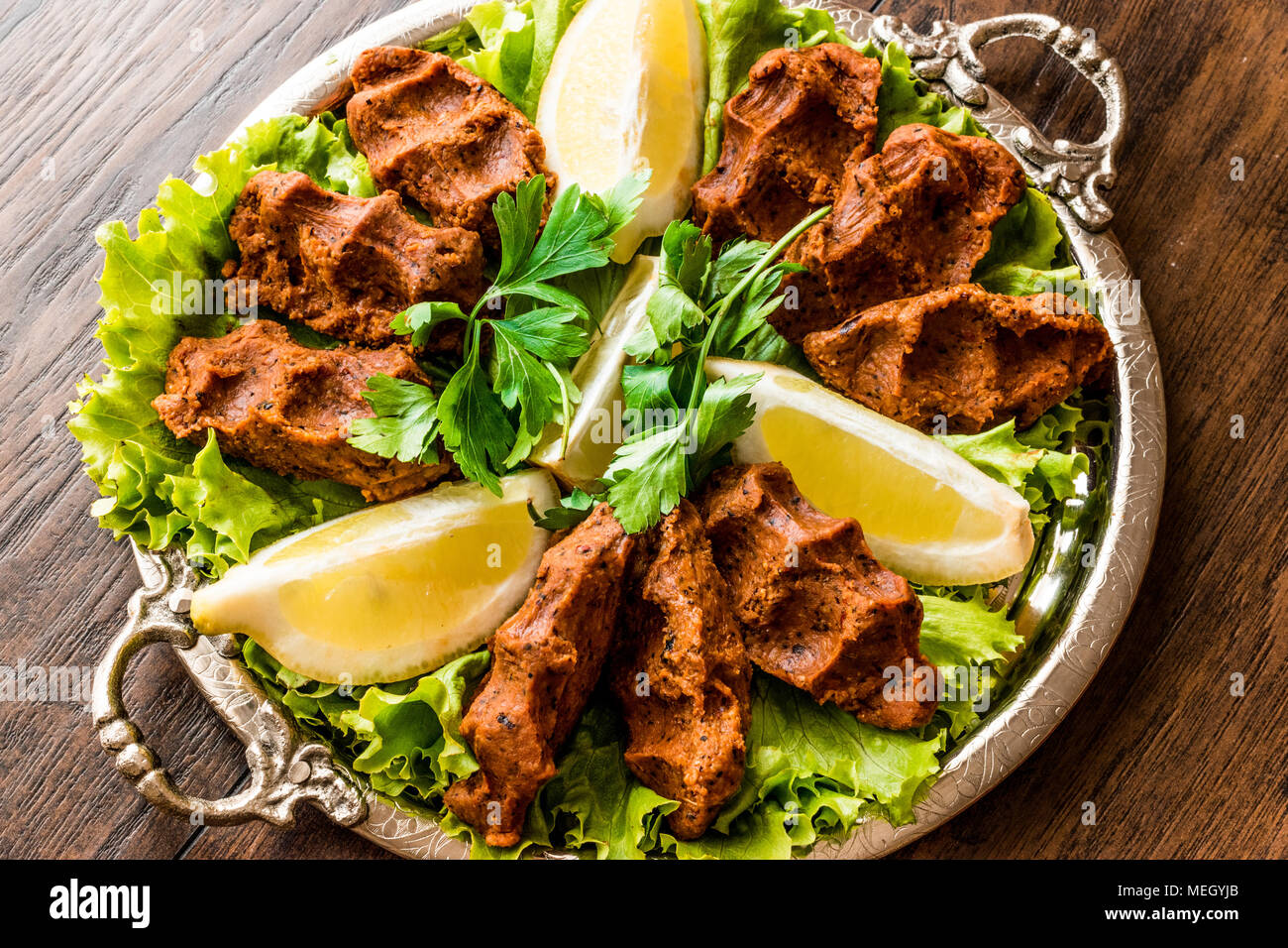 Türkische Lebensmittel Cig Köfte mit Zitrone, Salat und Petersilie auf Silber Fach traditionelles Essen Konzept. Stockfoto