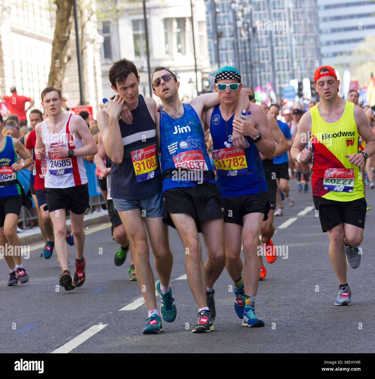 St James's Park, Birdcage Walk, London, UK. 22. April 2018. Elite und Tausende von fun Läufer in Richtung Buckingham Palace in brillanter Frühlingssonne, wie sie die letzte Meile der Virgin London Marathon 2018 eingeben. Einige der Teilnehmer waren betroffen, durch die einer der heißesten Marathons Tage auf und brauchten die Hilfe anderer Läufer die letzten km abzuschließen, als sie in der Mall, während andere angefahren wurden von Erste Hilfe Besatzungen behandelt. Leider einer der Läufer, Matt Campbell, 29 Jahren, brach nach 22,5 Meilen und starb später im Krankenhaus. Credit: Alan Fraser Stockfoto