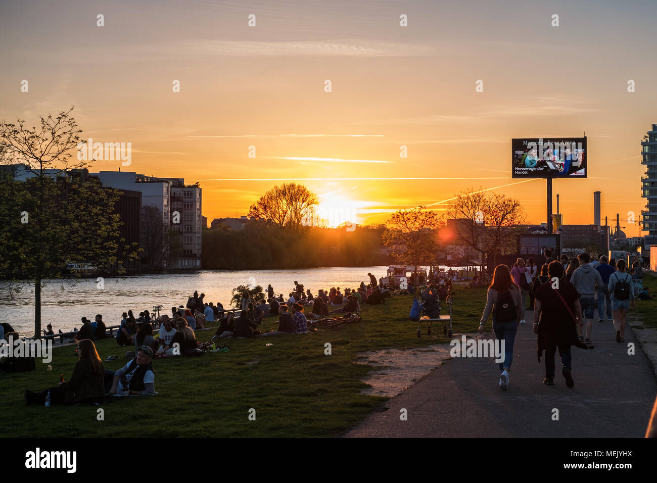 Berlin, Deutschland - April 2018: Junge Menschen zu Fuß an der Berliner Mauer (East Side Gallery) auf Sommer Tag abends bei Sonnenuntergang Himmel Stockfoto